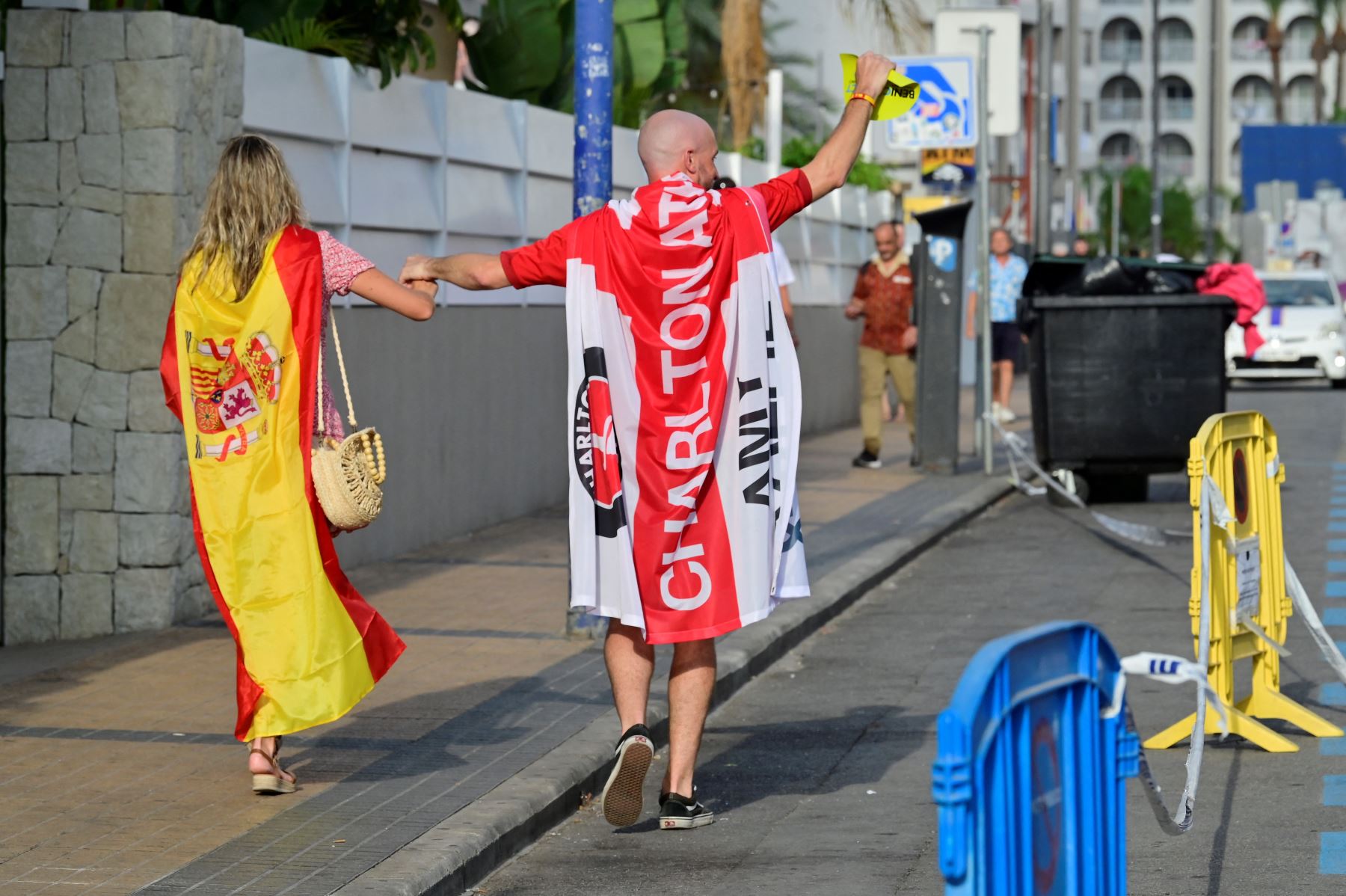 Los aficionados envueltos en el Charlton Athletic Football Club de Inglaterra y las banderas de España caminan antes del partido de fútbol final de la UEFA Euro 2024 entre España e Inglaterra, en Benidorm, costa este de España. AFP