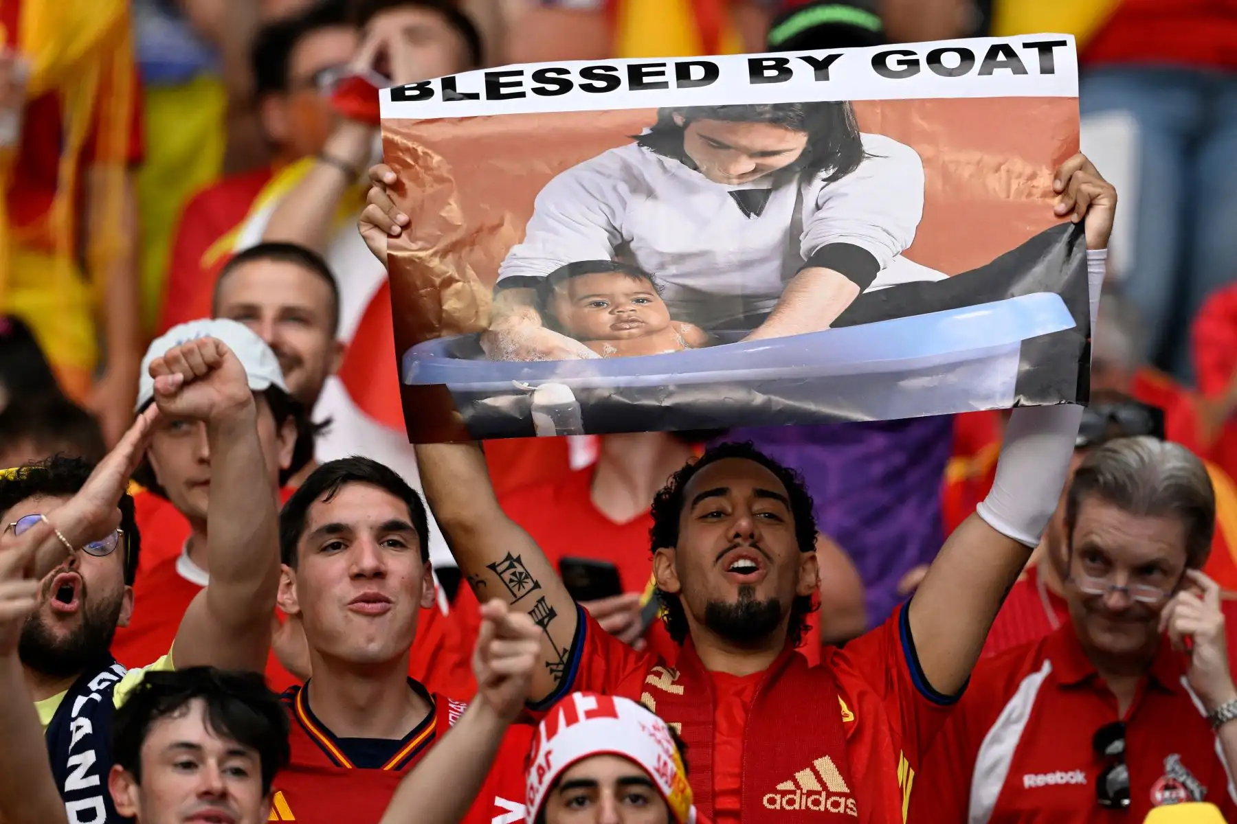 Un seguidor de España sostiene un cartel con una imagen que muestra al argentino Lionel Messi posando con el joven delantero español #19 Lamine Yamal, quien estaba visitando un vestuario de Barcelona como parte de una sesión de fotos del calendario benéfico en 2007 antes del partido de fútbol final de la UEFA Euro 2024. entre España e Inglaterra en el Olympiastadion de Berlín. AFP