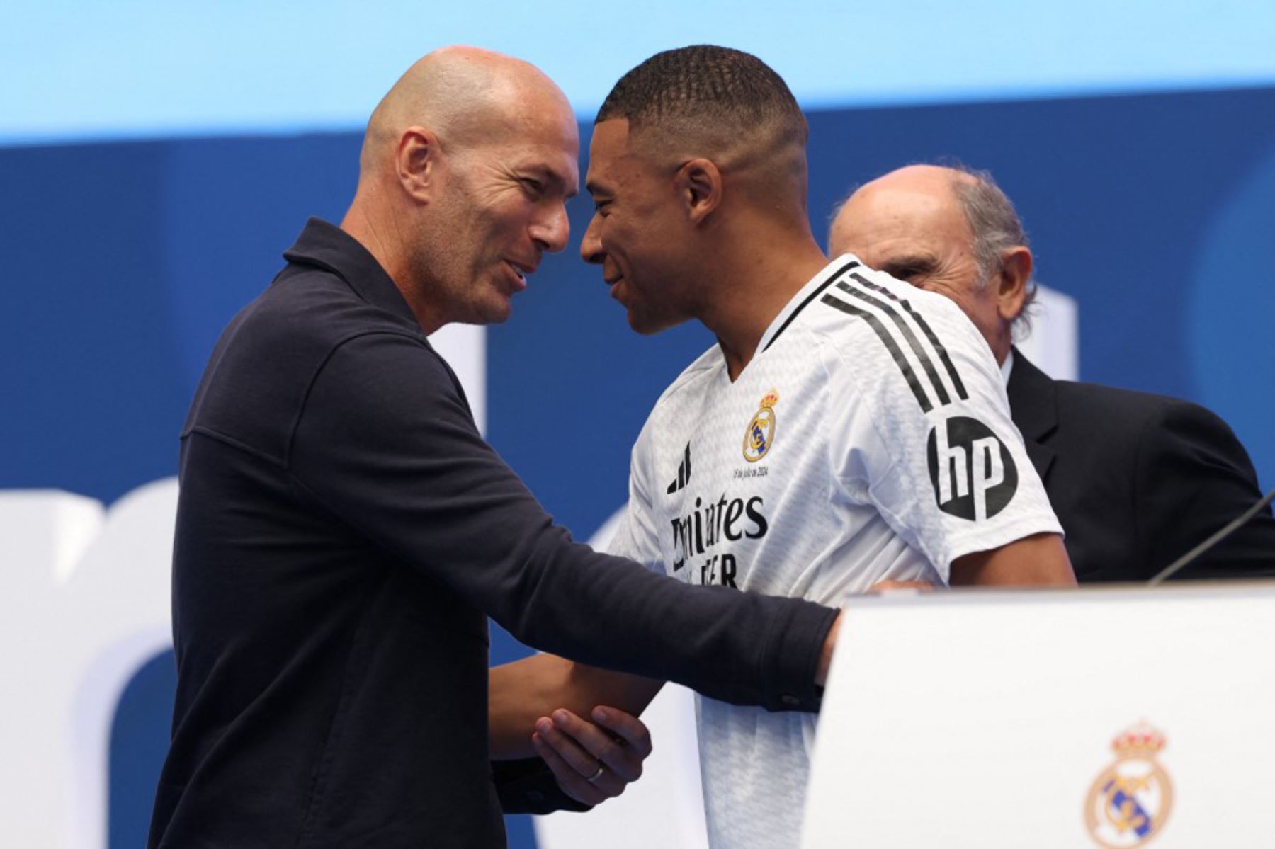 El delantero francés Kylian Mbappé es felicitado por el exfutbolista francés Zinedine Zidane, durante su primera aparición como jugador del Real Madrid en el estadio Santiago Bernabéu de Madrid el 16 de julio de 2024, tras firmar su nuevo contrato de cinco temporadas. Foto: AFP