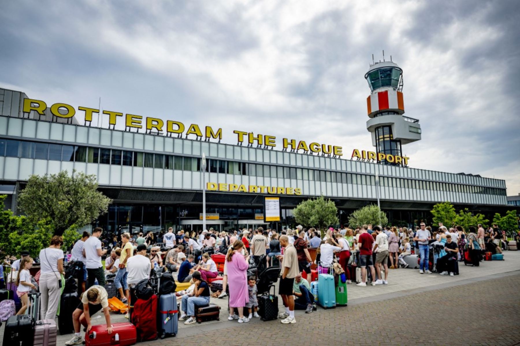 Los viajeros se encuentran afuera del aeropuerto de Rotterdam debido a un error que provocó una interrupción global de TI que afectó a los aeropuertos, lo que hizo imposible que la mayoría de los pasajeros realizaran el check-in. Foto: AFP