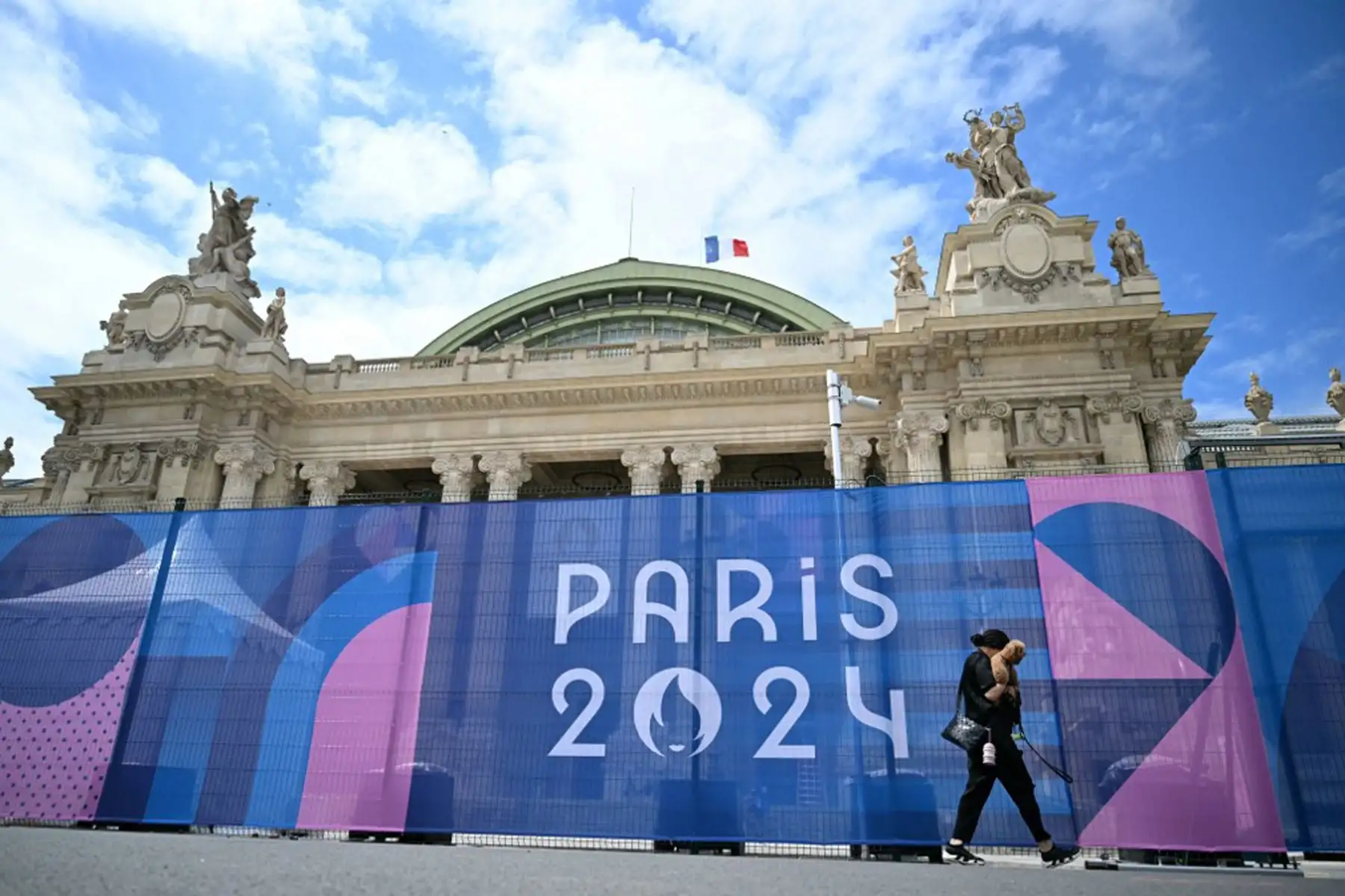 Un hombre camina junto a una valla con el logotipo de París 2024 frente al Grand Palais antes de los Juegos Olímpicos de París 2024.
Foto: AFP