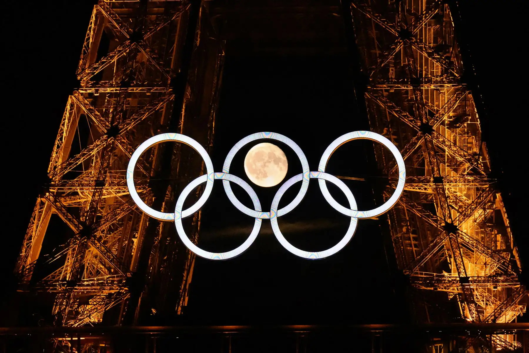 La luna sale detrás de los anillos olímpicos exhibidos en la Torre Eiffel de París el 22 de julio de 2024. Foto: ANDINA/AFP
