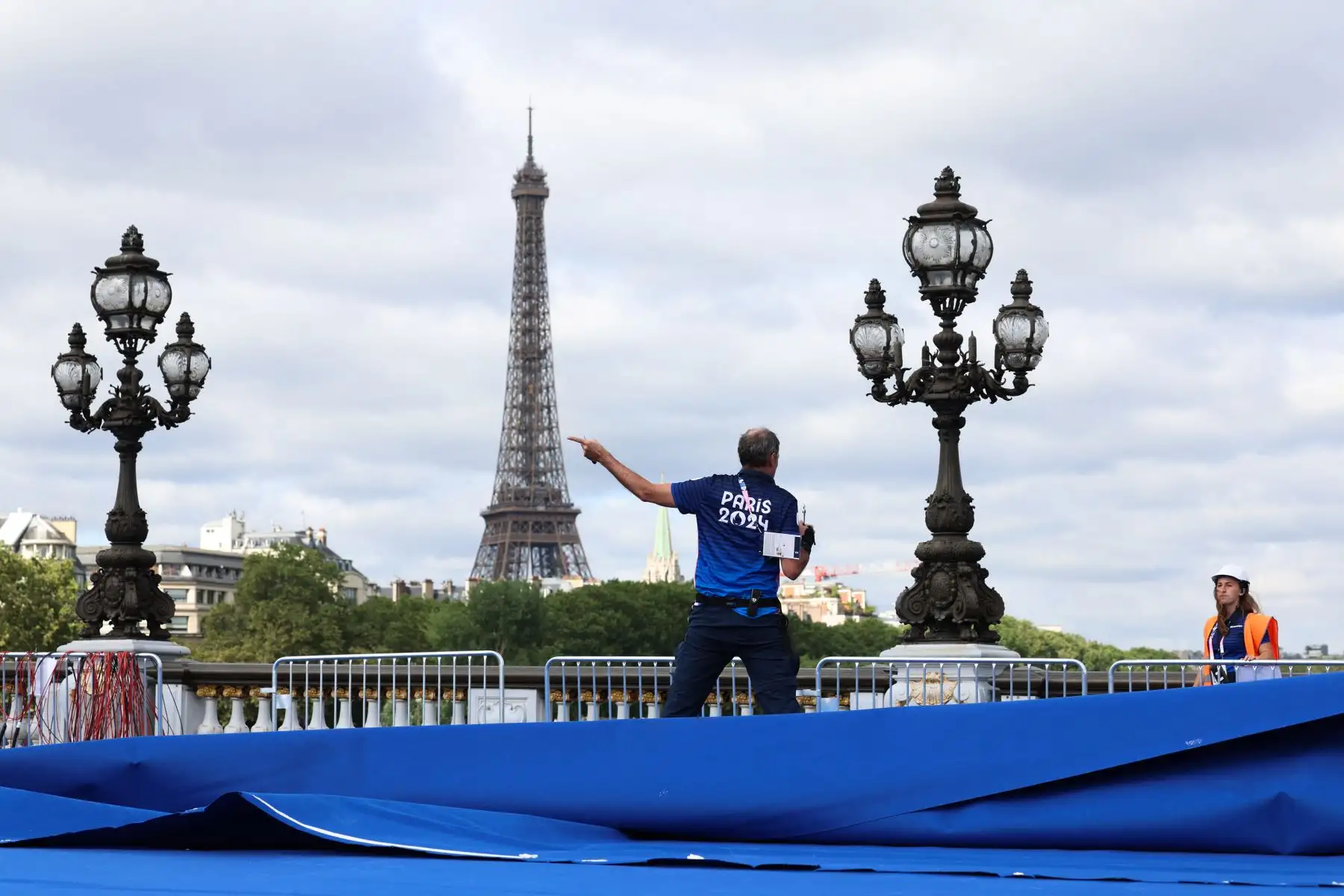 Los empleados de los Juegos Olímpicos y Paralímpicos de París 2024 trabajan para instalar la pista de triatlón en el puente Alexandre III con la Torre Eiffel al fondo en París, antes de los próximos Juegos Olímpicos y Paralímpicos de París 2024. Foto: ANDINA/AFP