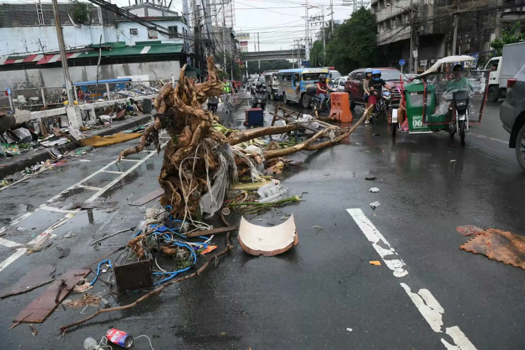 Los automovilistas pasan junto al tronco de un árbol arrastrado por una calle de Manila, en el punto álgido de las inundaciones en medio de las fuertes lluvias provocadas por el tifón Gaemi. Foto: AFP