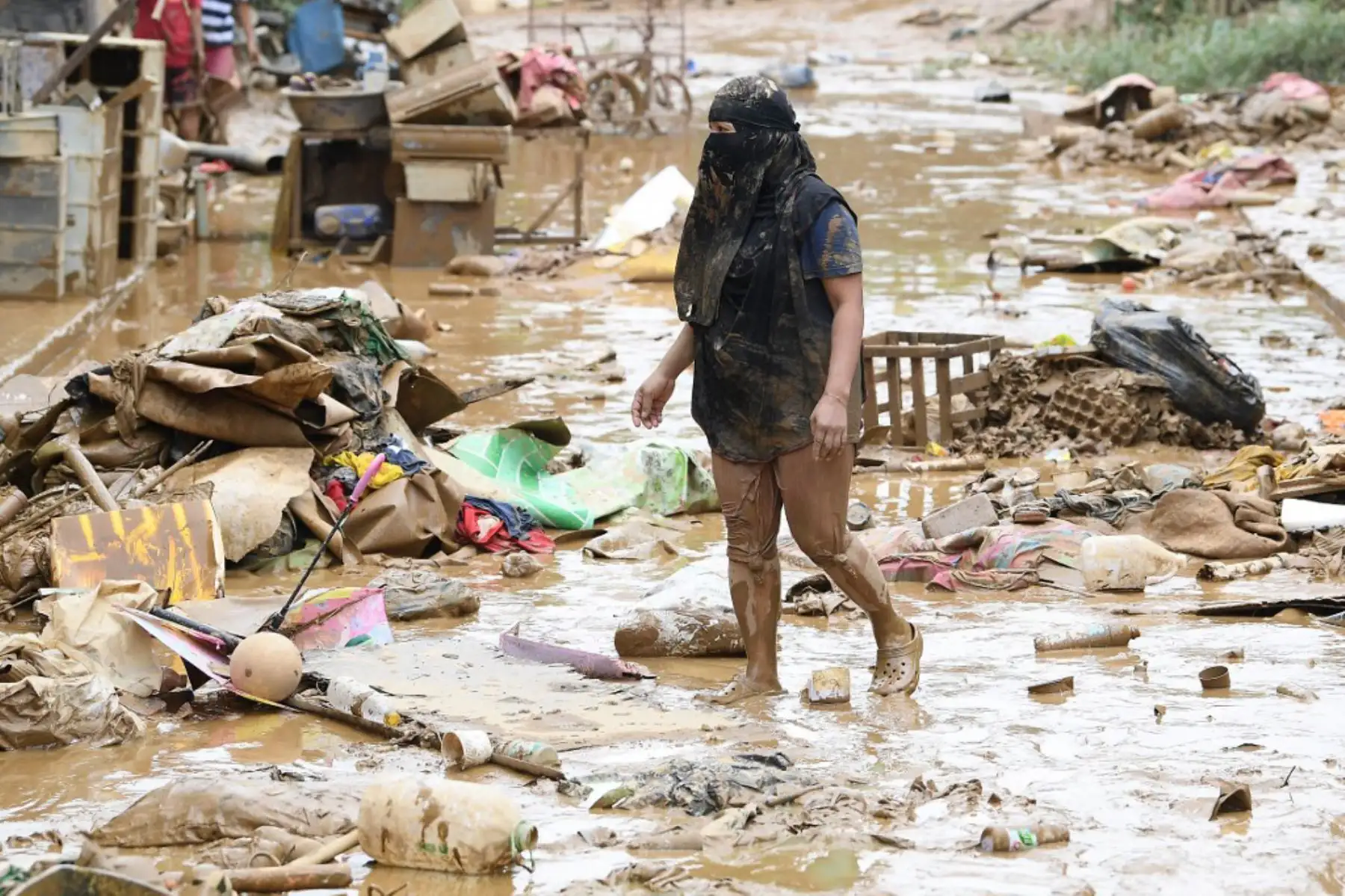 Una residente camina entre los escombros de sus pertenencias destruidas junto a su casa en un pueblo de Manila, un día después de que las fuertes lluvias provocadas por el tifón Gaemi y el monzón estacional azotaran Manila y las regiones circundantes en los últimos días. Foto: AFP
