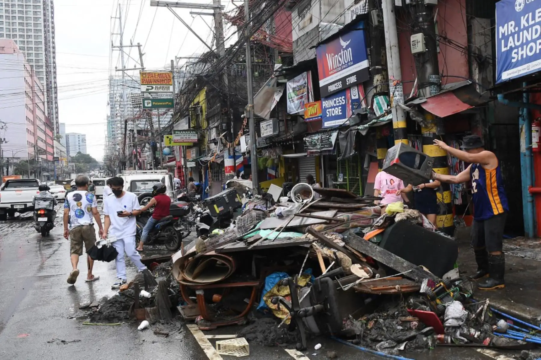 Un residente arroja un microondas destruido en medio de las inundaciones en una carretera de Manila. Foto: AFP