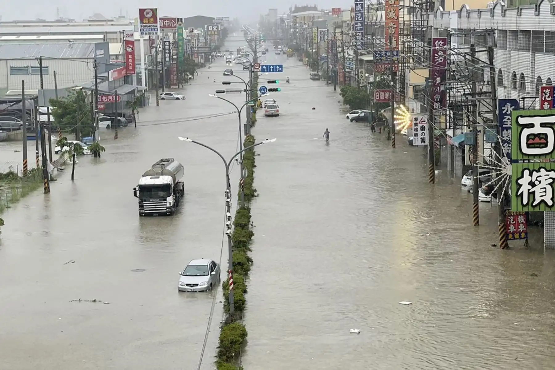 Personas y vehículos caminan por el agua a lo largo de una calle inundada por el tifón Gaemi en Kaohsiung. El tifón, el más fuerte que ha azotado Taiwán en ocho años, ya había obligado a las autoridades de la isla a cerrar escuelas y oficinas, suspender la bolsa y evacuar a miles de personas. Foto: AFP