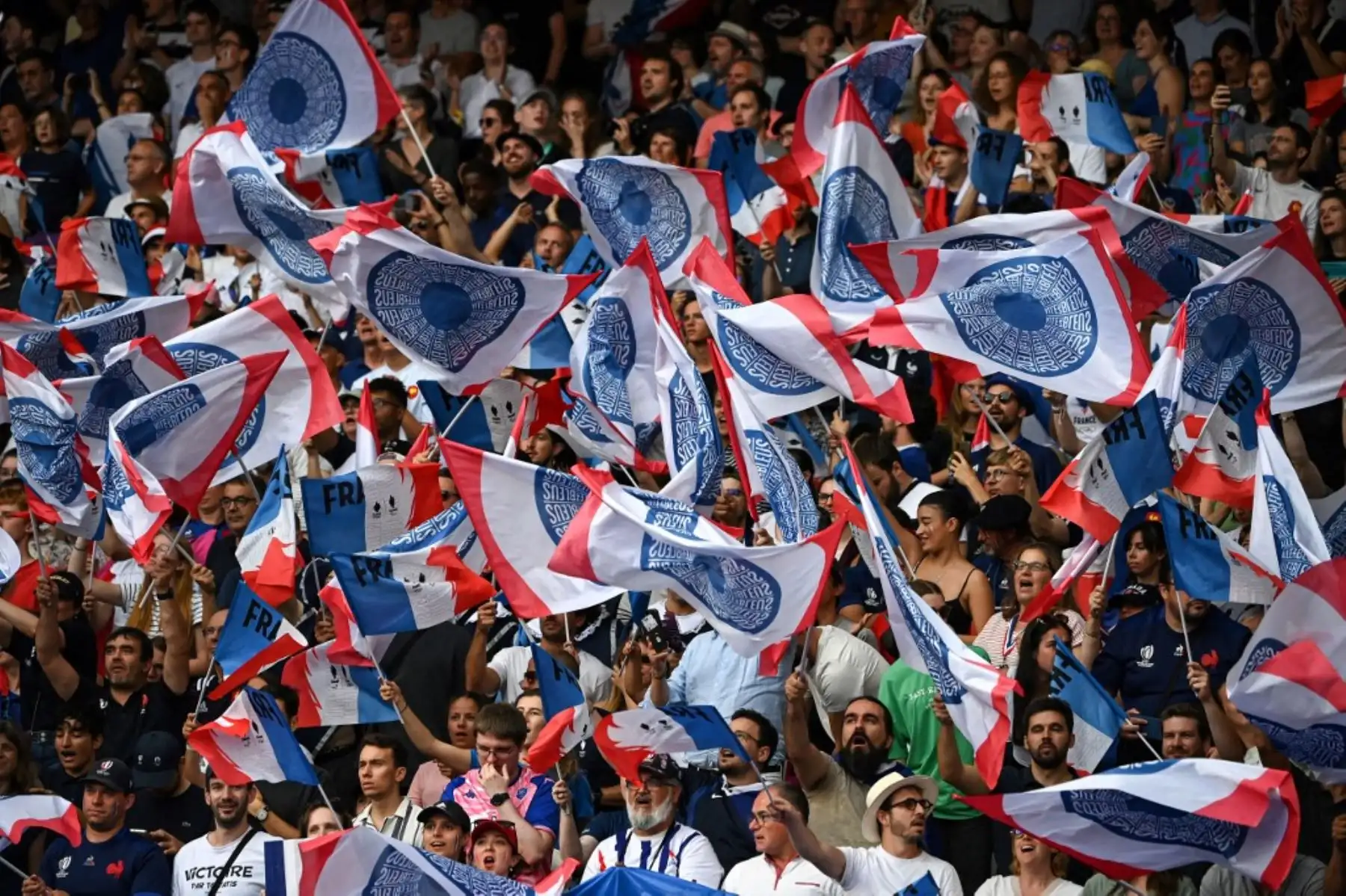 Hinchas franceses ondean banderas mientras alientan a su selección en el partido de rugby seven masculino del grupo C entre Francia y Uruguay en los Juegos Olímpicos de París 2024 en el Stade de France en Saint-Denis el 24 de julio de 2024. Foto: AFP