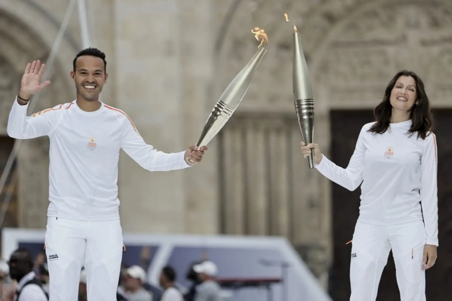El presentador de televisión y periodista de France Television, Mohamed Bouhafsi, y la actriz francesa Laetitia Casta sostienen la antorcha olímpica como parte del relevo de la antorcha de los Juegos Olímpicos de París 2024, durante la inauguración en Saint-Denis, el 26 de julio. Foto: AFP