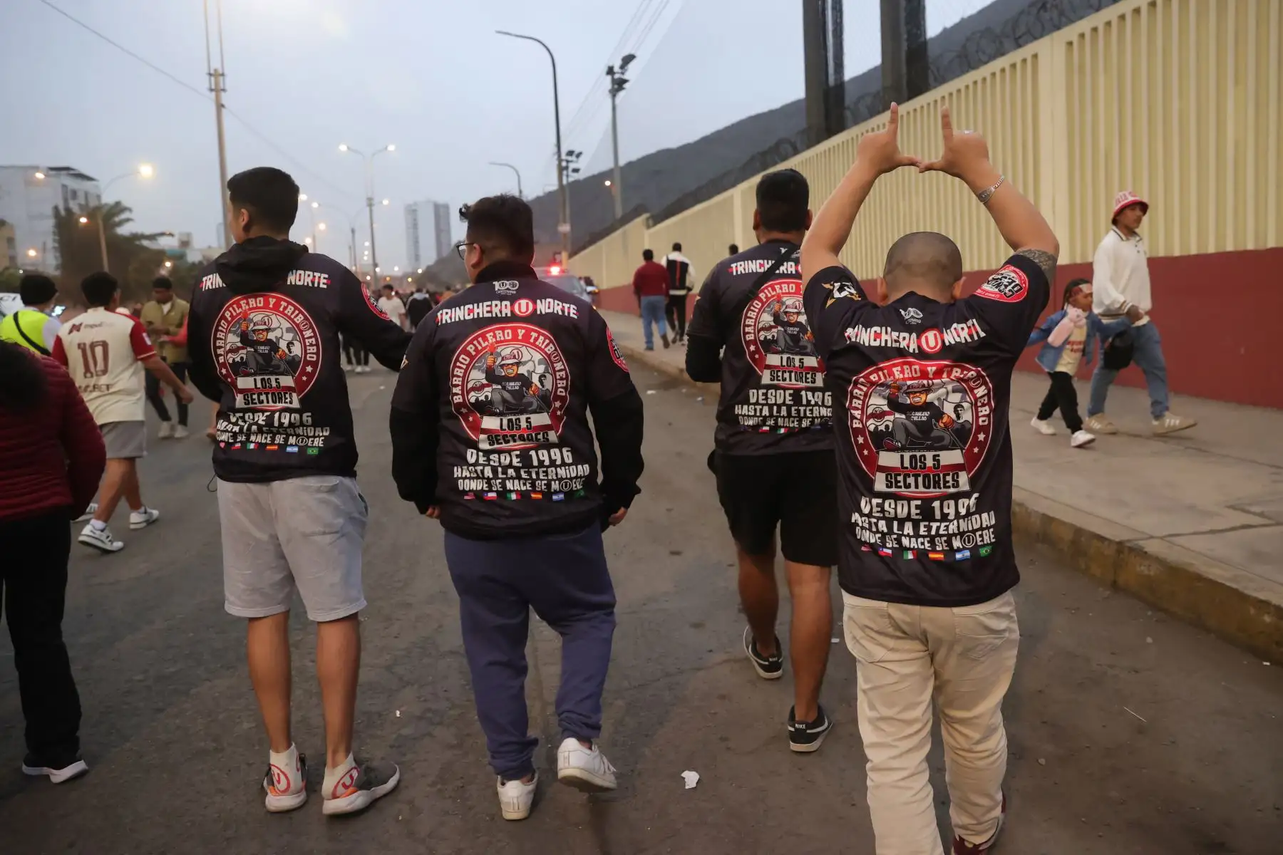 Hinchas de Universitario de Deportes alientan a su equipo en los exteriores del Estadio Monumental "U" de Ate momentos previos al clásico del fútbol peruano con Alianza Lima, partido por el Torneo Clausura de la Liga 1. Foto: ANDINA/Melina Mejía