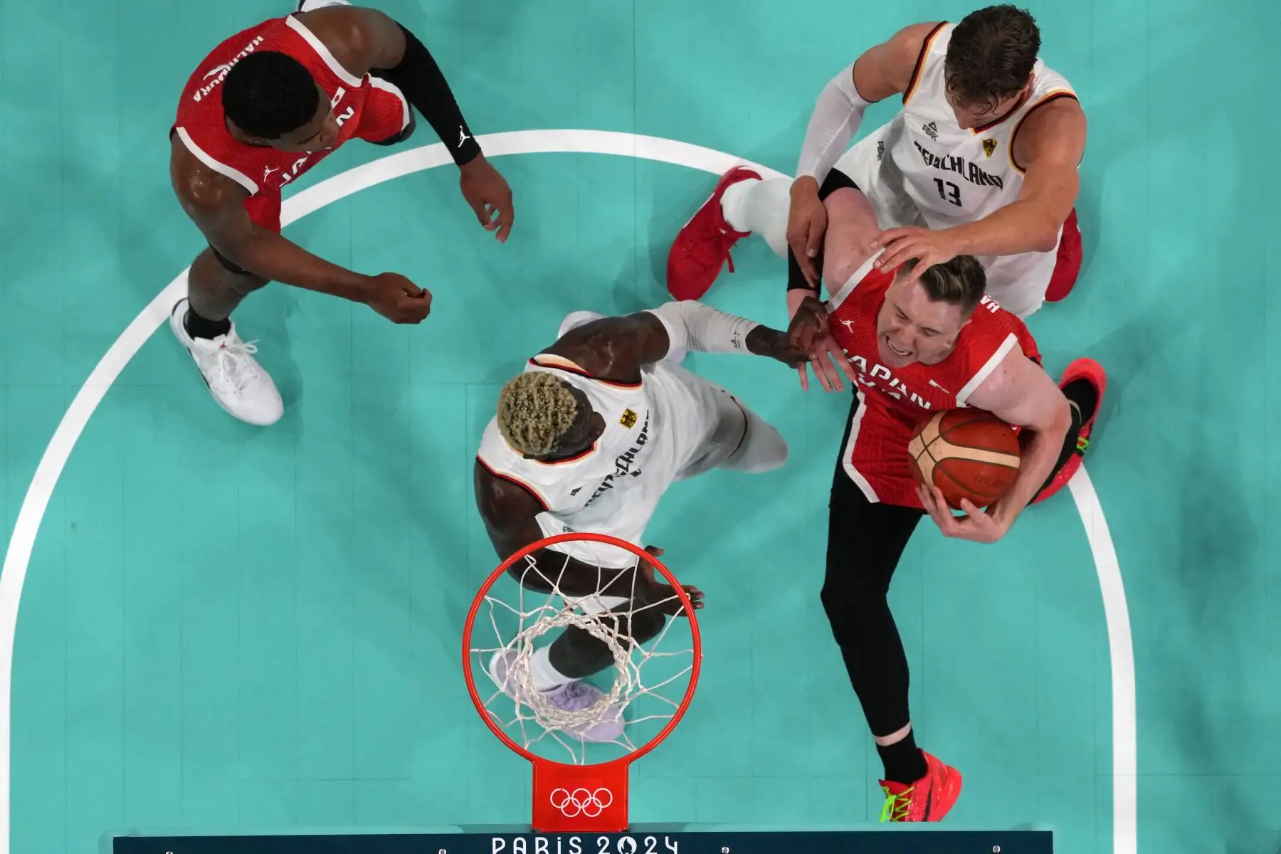 Una descripción general muestra al alemán Isaac Bonga  y al alemán Moritz Wagner defendiéndose contra el japonés Josh Hawkinson en el partido de baloncesto del grupo B de la ronda preliminar masculina entre Alemania y Japón durante los Juegos Olímpicos de París 2024. AFP