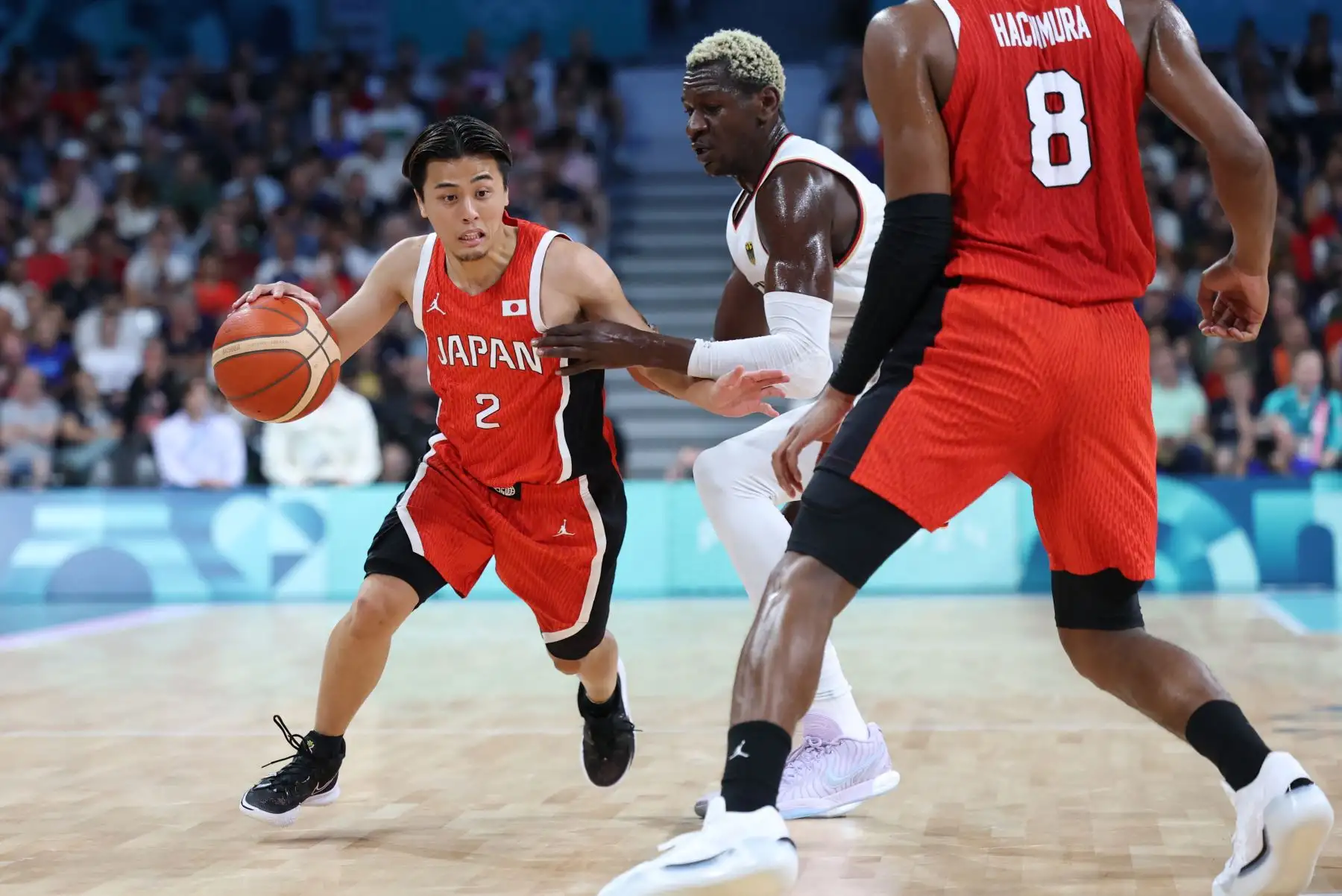 El japonés Yuki Togashi trabaja alrededor del alemán Isaac Bonga en el partido de baloncesto del grupo B de la ronda preliminar masculina entre Alemania y Japón durante los Juegos Olímpicos de París 2024. AFP