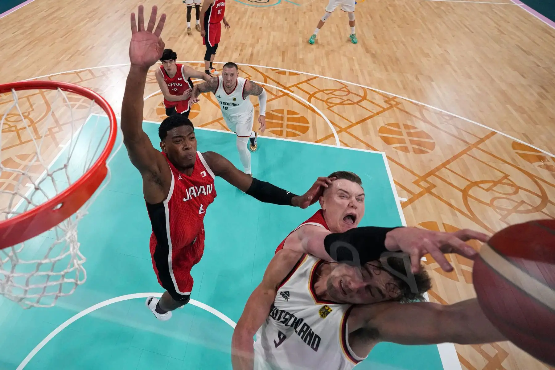 Una descripción general muestra al japonés Rui Hachimura y al japonés Josh Hawkinson defendiendo contra el alemán  Franz Wagneren el partido de baloncesto del grupo B de la ronda preliminar masculina entre Alemania y Japón durante los Juegos Olímpicos de París 2024. AFP