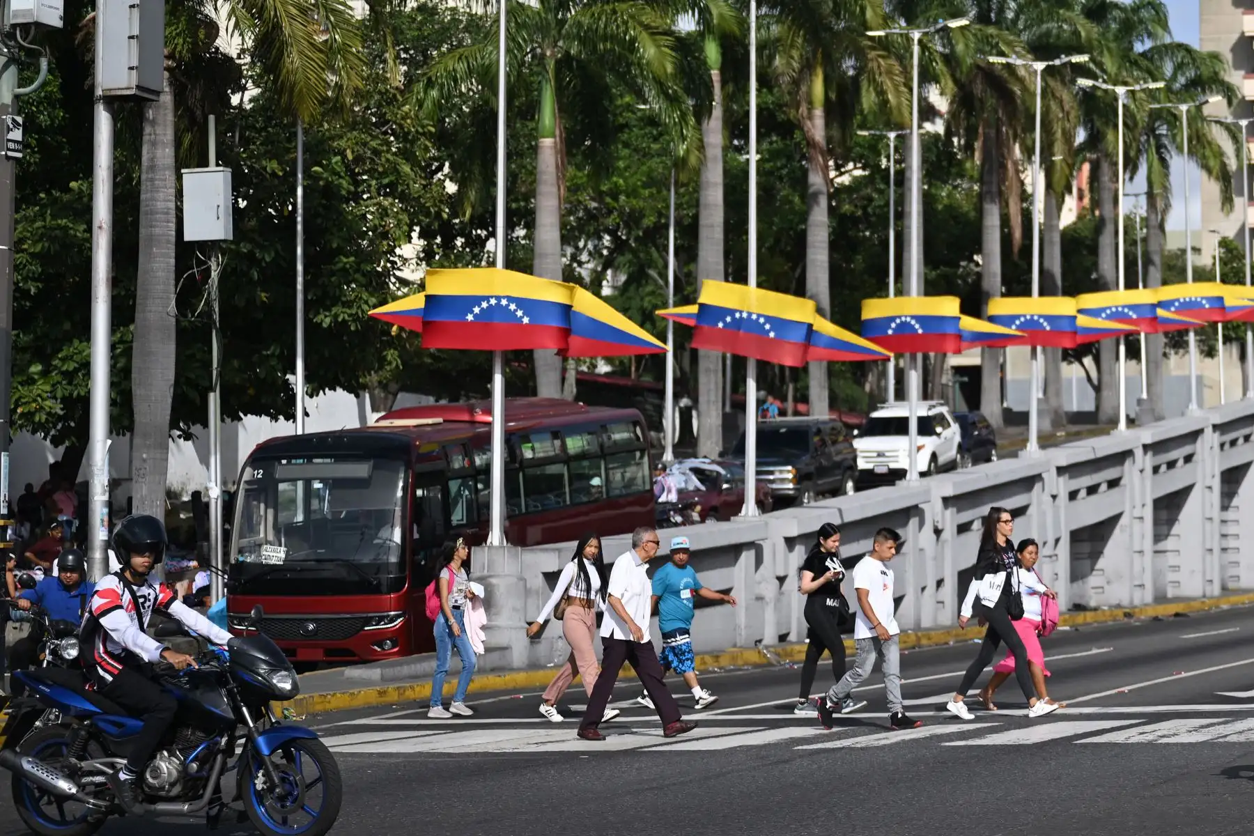 La gente cruza una calle cerca de una pancarta con la imagen del fallecido presidente venezolano Hugo Chávez en Caracas. Venezuela celebrará elecciones presidenciales el 28 de julio de 2024.
Foto: AFP