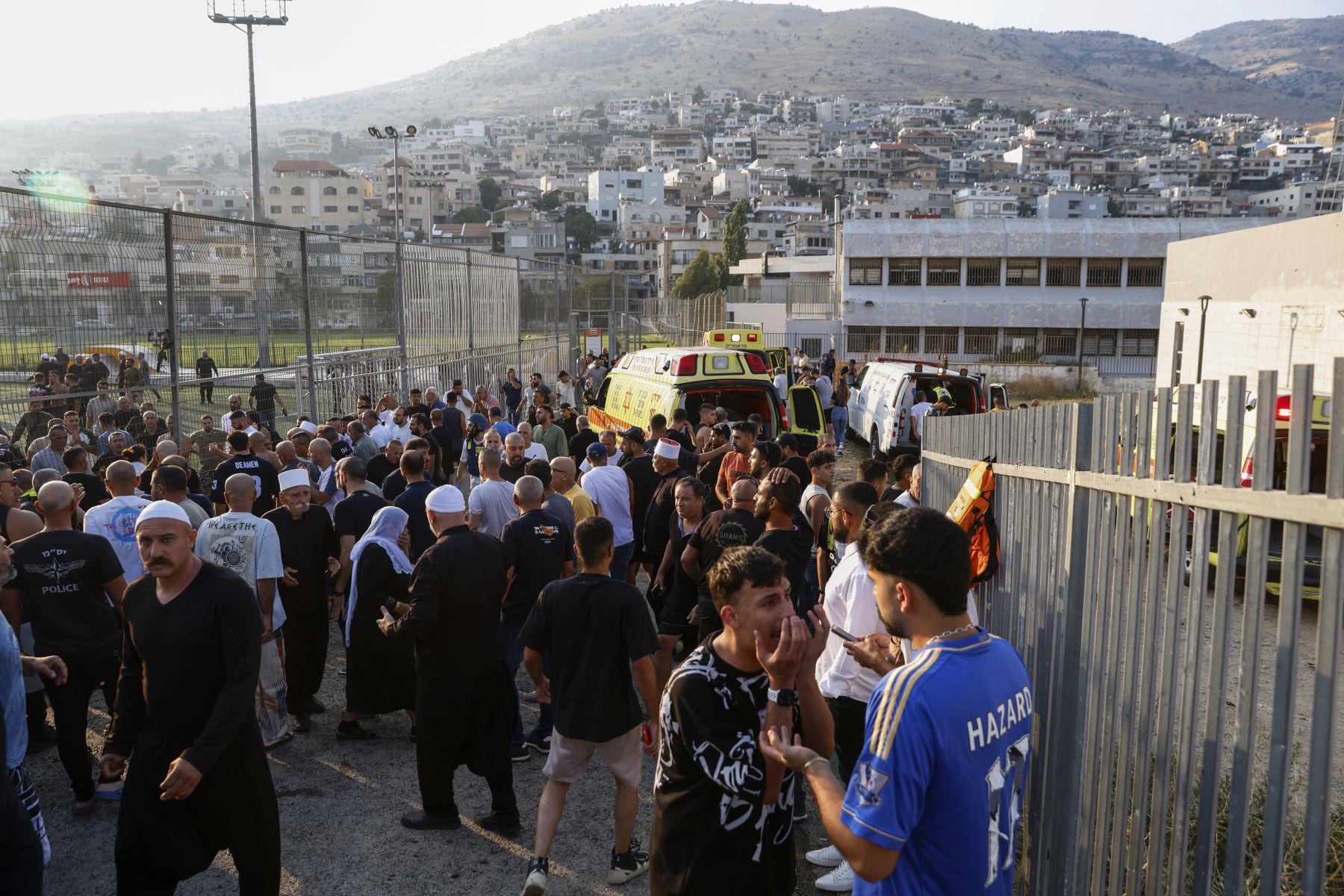 Los servicios de emergencia israelíes y los residentes locales se reúnen cerca de un lugar donde cayó un ataque desde el Líbano en la aldea de Majdal Shams en el área del Golán anexada por Israel.
Foto: AFP
