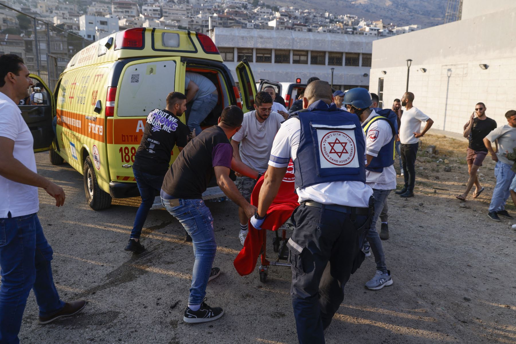 Las fuerzas de seguridad y los médicos israelíes transportan a las víctimas junto con los residentes locales, en un lugar donde se informó que cayó un ataque desde el Líbano en la aldea de Majdal Shams en el área del Golán anexada por Israel.
Foto: AFP