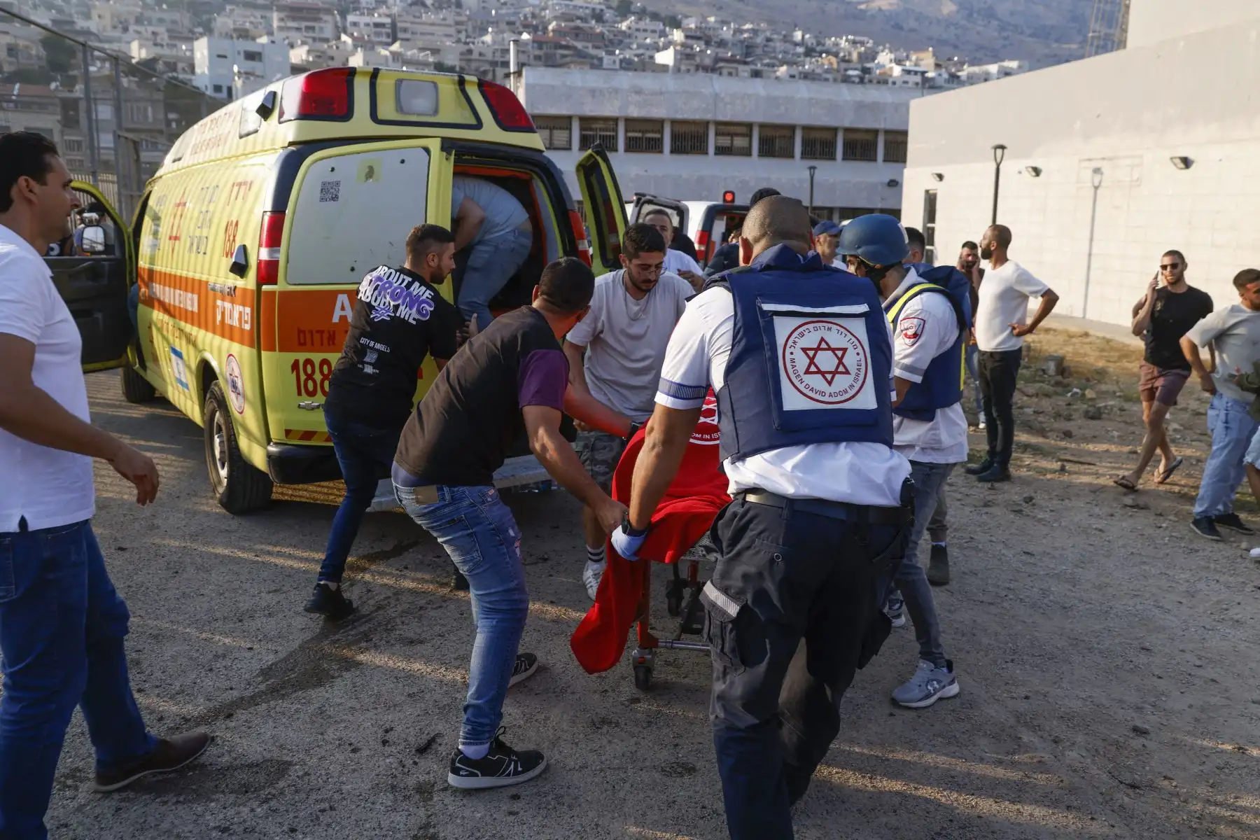 Las fuerzas de seguridad y los médicos israelíes transportan a las víctimas junto con los residentes locales, en un lugar donde se informó que cayó un ataque desde el Líbano en la aldea de Majdal Shams en el área del Golán anexada por Israel.
Foto: AFP