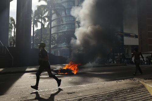 Un manifestante corre durante enfrentamientos entre opositores y miembros de la Guardia Nacional Bolivariana, por los resultados de las elecciones presidenciales este lunes, en Caracas (Venezuela). Foto: EFE