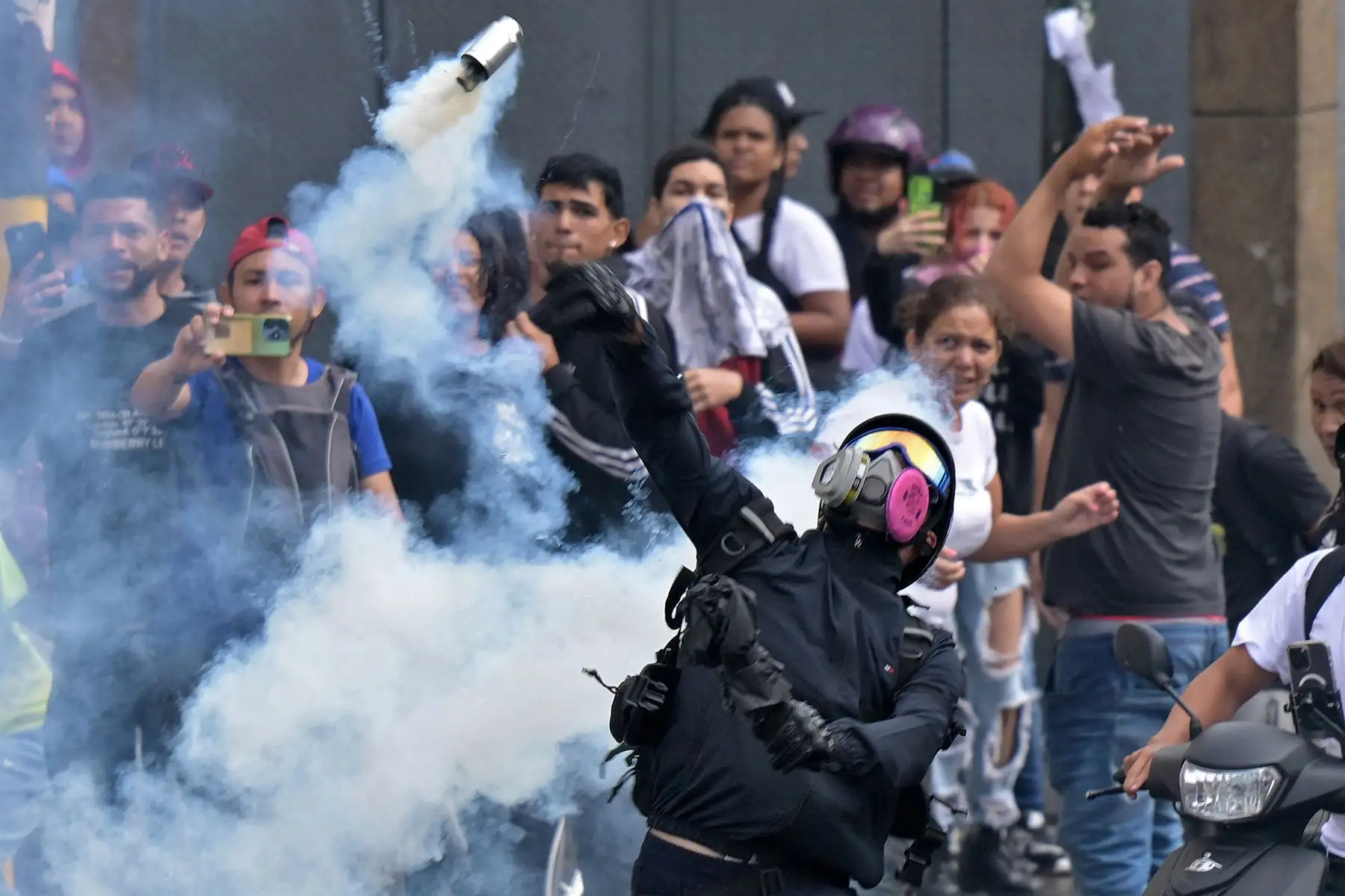 Opositores al gobierno del presidente venezolano Nicolás Maduro se enfrentan con la policía antidisturbios durante una protesta en el barrio 00 un día después de las elecciones presidenciales venezolanas. 
Foto: AFP