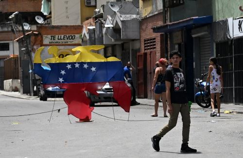 Un hombre camina frente a un mapa venezolano decorado con los colores de la bandera venezolana en Caracas el 30 de julio de 2024. Foto: AFP
