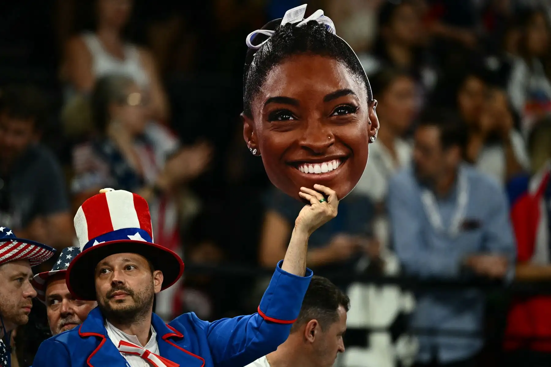 Un aficionado sostiene una fotografía de la estadounidense Simone Biles durante la final femenina por equipos de gimnasia artística durante los Juegos Olímpicos de París 2024.
Foto: ANDINA/AFP