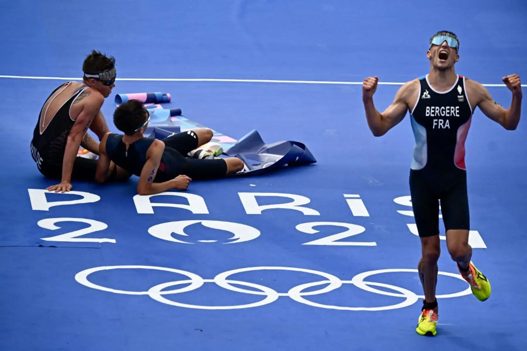 El francés Leo Bergere reacciona junto al británico Alex Yee y al neozelandés Hayden Wilde después de terminar la carrera de triatlón individual masculino en los Juegos Olímpicos de París 2024. Foto: AFP