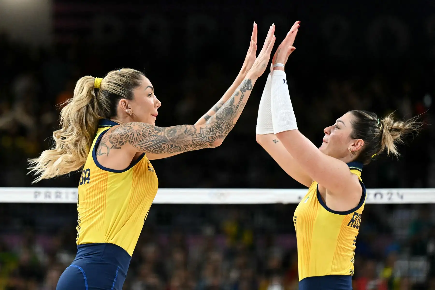 La brasileña Thaisa Daher De Menezes y la brasileña Rosamaría Montibeller rse dan aánimos la una a la otra antes del inicio del partido de voleibol de la ronda preliminar femenina entre Brasil y Japón durante los Juegos Olímpicos de París 2024 en el South Paris Arena 1 en París el 1 de agosto. Foto: AFP