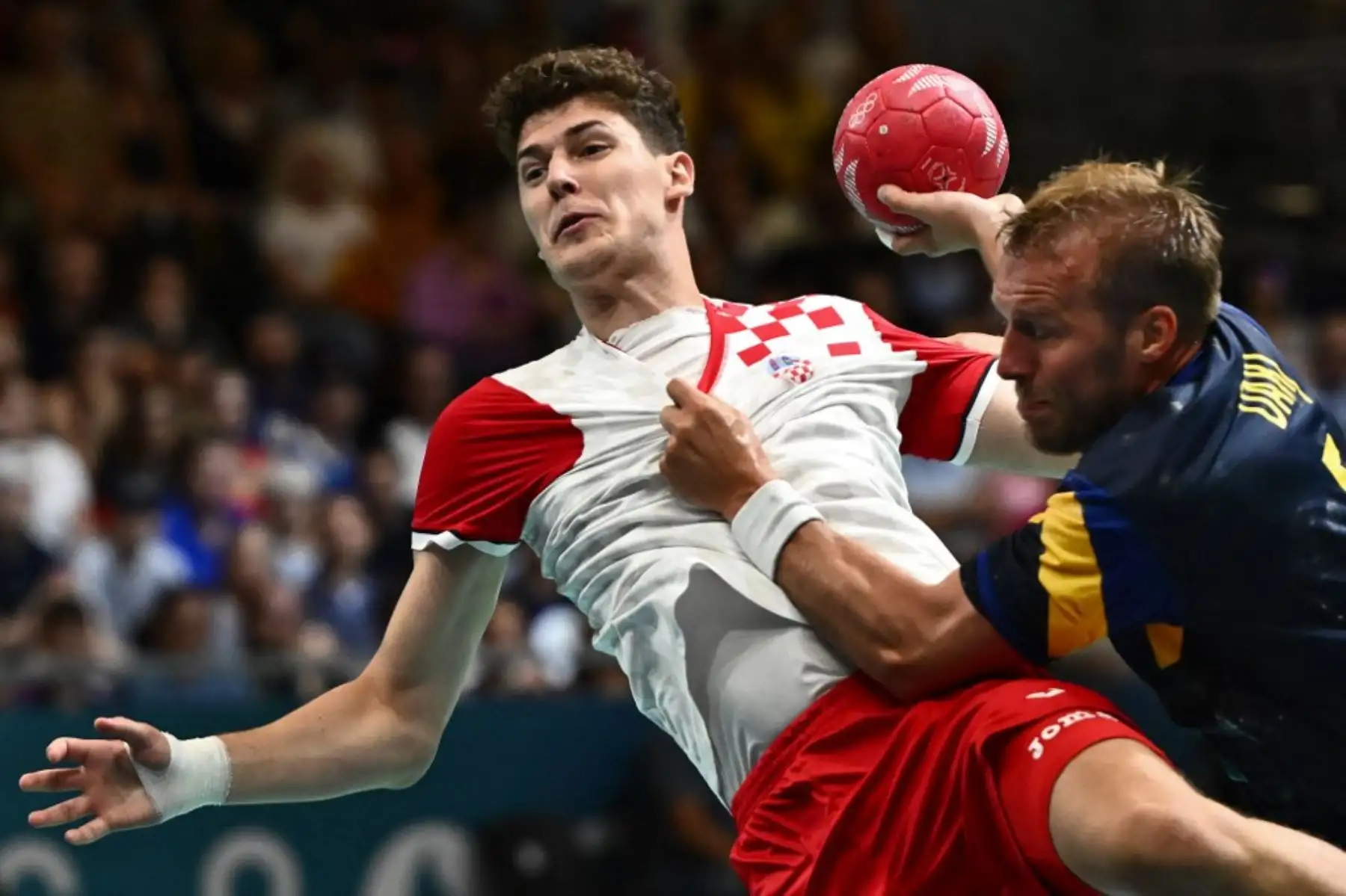 El lateral derecho de Croacia Luka Lovre Klarica se enfrenta al pivote sueco Max Darj durante el partido de balonmano del Grupo A de la Ronda Preliminar masculina entre Croacia y Suecia de los Juegos Olímpicos de París 2024, en el Paris South Arena. Foto: AFP