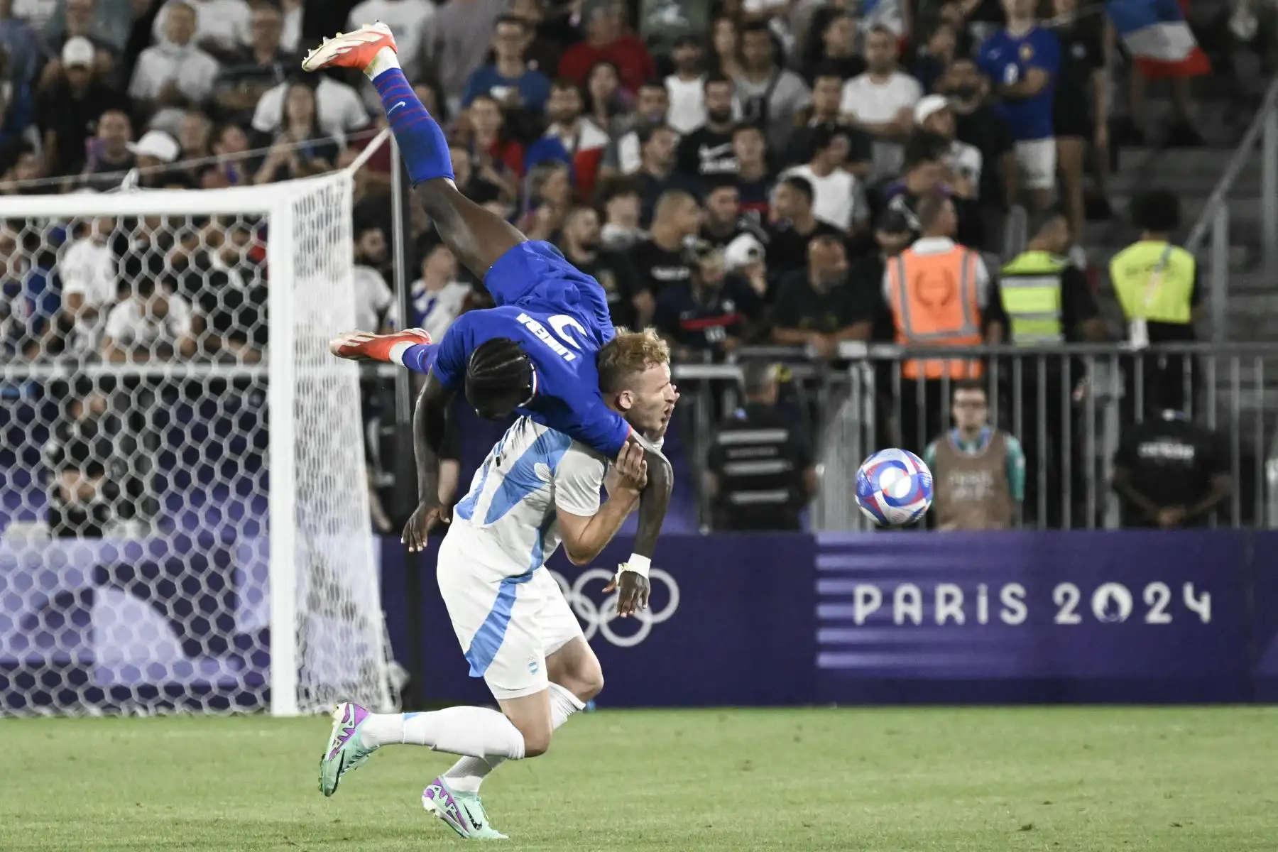 El defensor francés  Castello Lukeba cae sobre el delantero argentino Luciano Gondou en el partido de fútbol masculino de cuartos de final entre Francia y Argentina durante los Juegos Olímpicos de París 2024. Foto: AFP