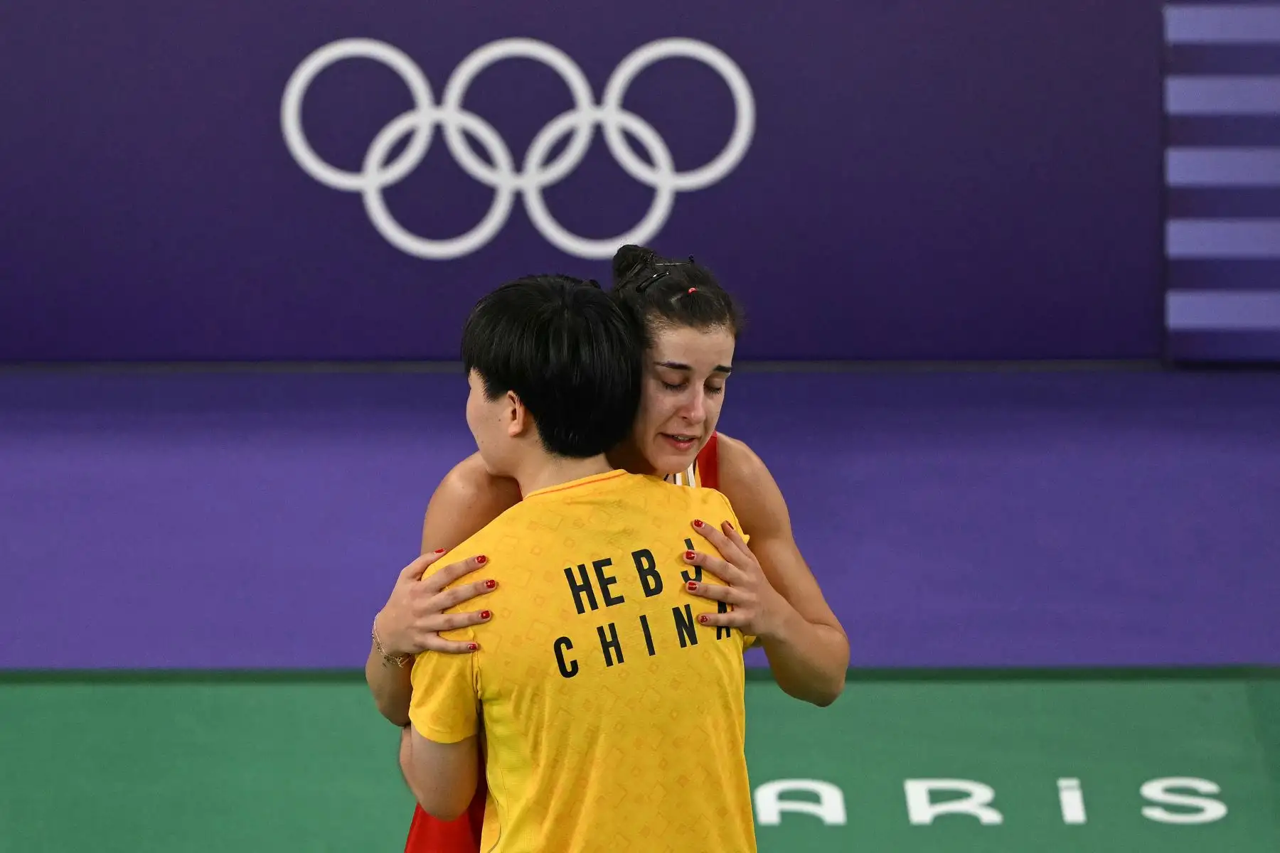 La china He Bing Jiao consuela a la española Carolina Marín mientras sale de la cancha con una rodillera después de conceder su partido de semifinal de bádminton individual femenino tras una lesión durante los Juegos Olímpicos de París 2024. AFP