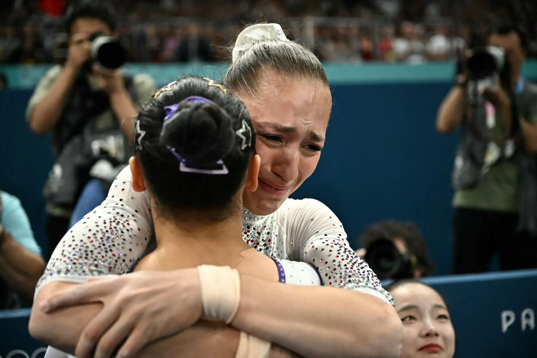 La argelina Kaylia Nemour es felicitada por la china Qiu Qiyuan tras competir en la final de barras asimétricas femeninas de gimnasia artística durante los Juegos Olímpicos de París 2024. AFP