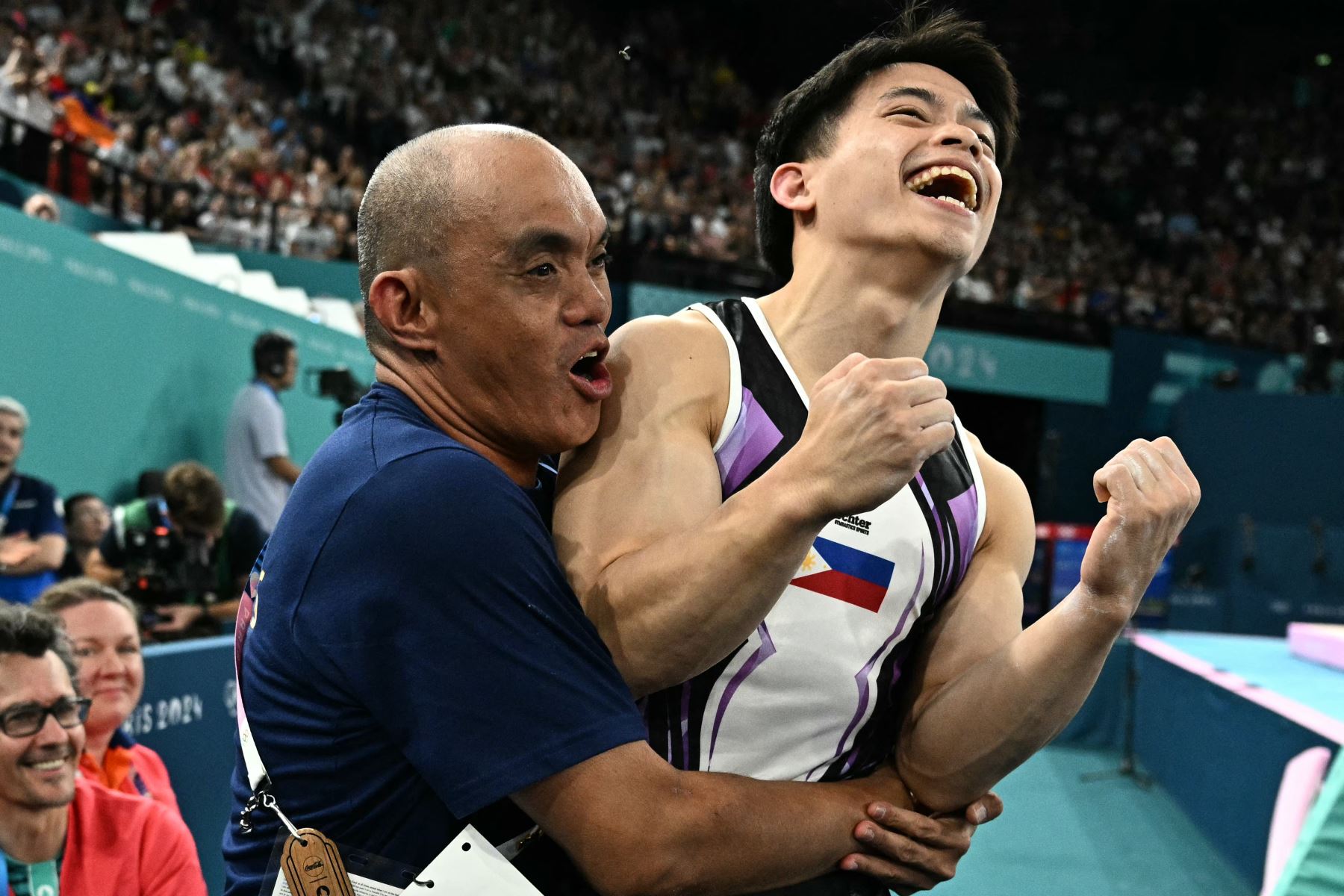 Carlos Edriel Yulo, de Filipinas, celebra con su entrenador haber ganado la medalla de oro al final de la final de anillos masculinos de gimnasia artística durante los Juegos Olímpicos de París 2024. AFP