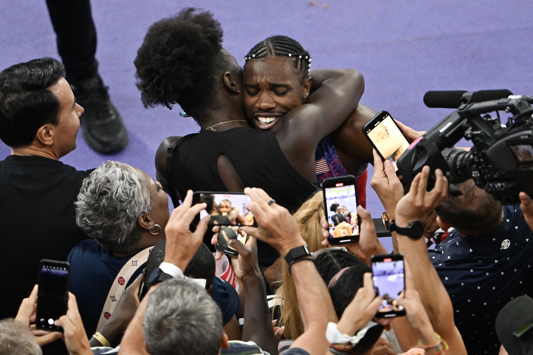 Los periodistas rodean al estadounidense Noah Lyles mientras celebra con su familia después de ganar la final masculina de 100 metros del evento de atletismo en los Juegos Olímpicos de París 2024 en el Stade de France en Saint-Denis, al norte de París.
Foto: AFP