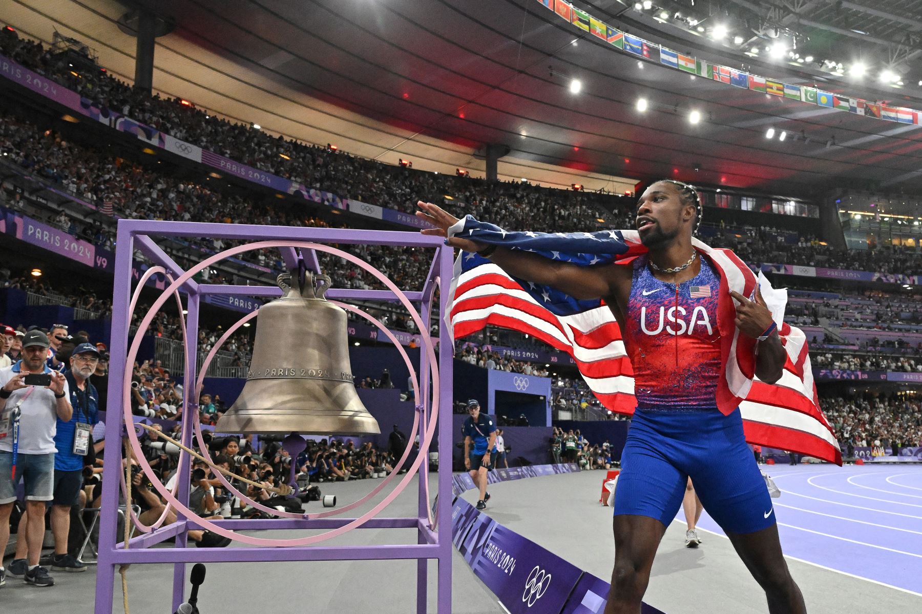 El estadounidense Noah Lyles toca la campana de París 2024 mientras celebra después de ganar la final masculina de 100 metros del evento de atletismo en los Juegos Olímpicos de París 2024 en el Stade de France en Saint-Denis, al norte de París.
Foto: AFP