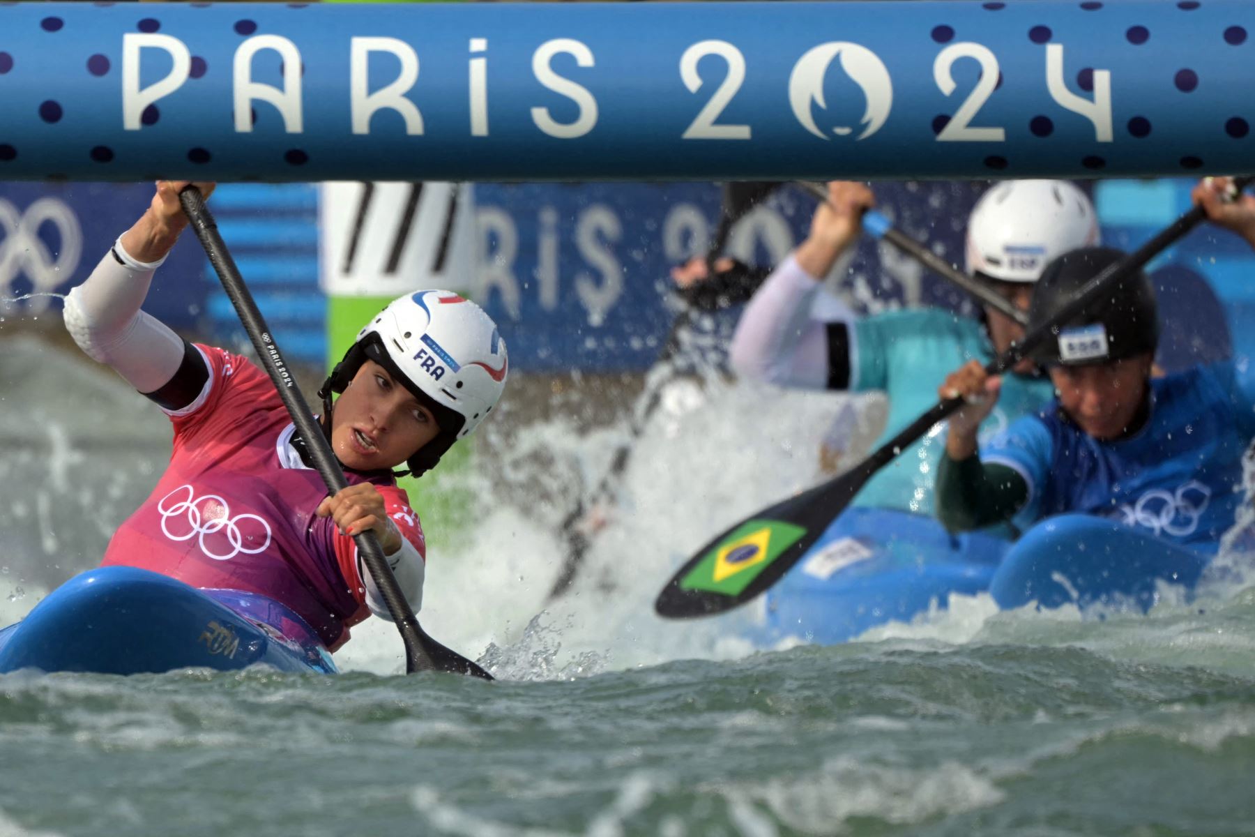 La francesa Angele Hug  se adelanta a la brasileña Ana Satila y a la española Miren Lazkano en la competición femenina de kayak cross calienta canoa slalom en el estadio náutico de Vaires-sur-Marne en Vaires-sur-Marne durante los Juegos Olímpicos de París 2024.
Foto: AFP