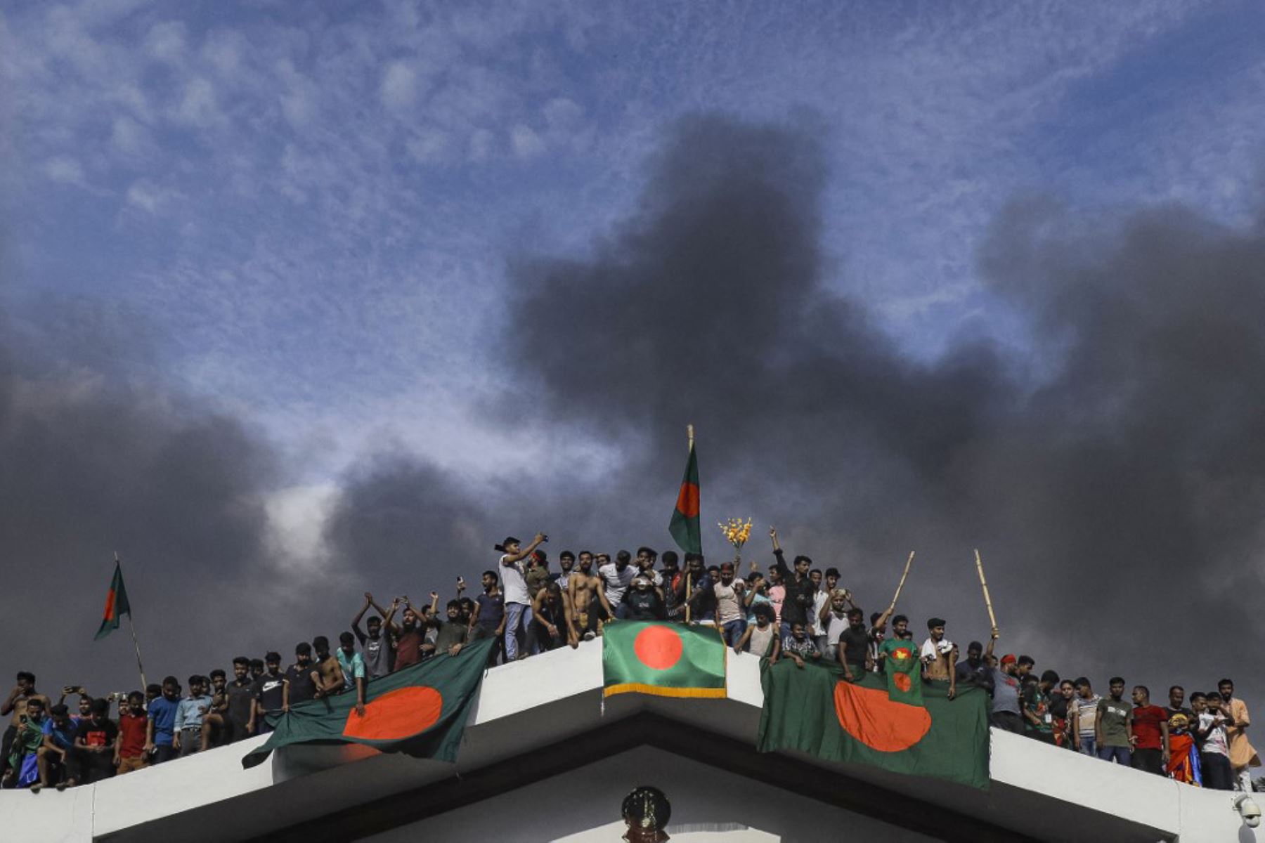 Manifestantes antigubernamentales exhiben la bandera nacional de Bangladesh mientras asaltan el palacio de la primera ministra Sheikh Hasina en Dhaka. Foto: AFP