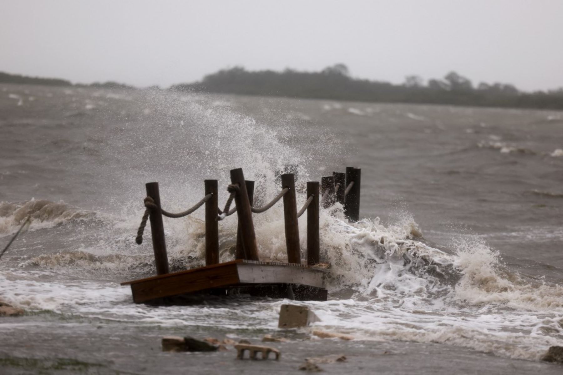 Las olas rompen contra un muelle mientras los fuertes vientos, la lluvia y la marejada ciclónica del huracán Debby inundan un vecindario  en Cedar Key, Florida. Foto: AFP