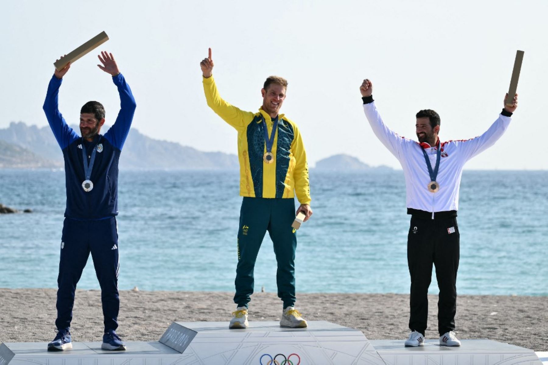 Pavlos Kontides, medallista de plata de Chipre, Matt Wearn, medallista de oro de Australia, y Stefano Peschiera, medallista de bronce de Perú, posan en el podio durante la ceremonia de premiación del evento de bote ligero masculino ILCA 7 durante la competencia de vela de los Juegos Olímpicos de París 2024 en el puerto deportivo de Roucas-Blanc. Foto: AFP