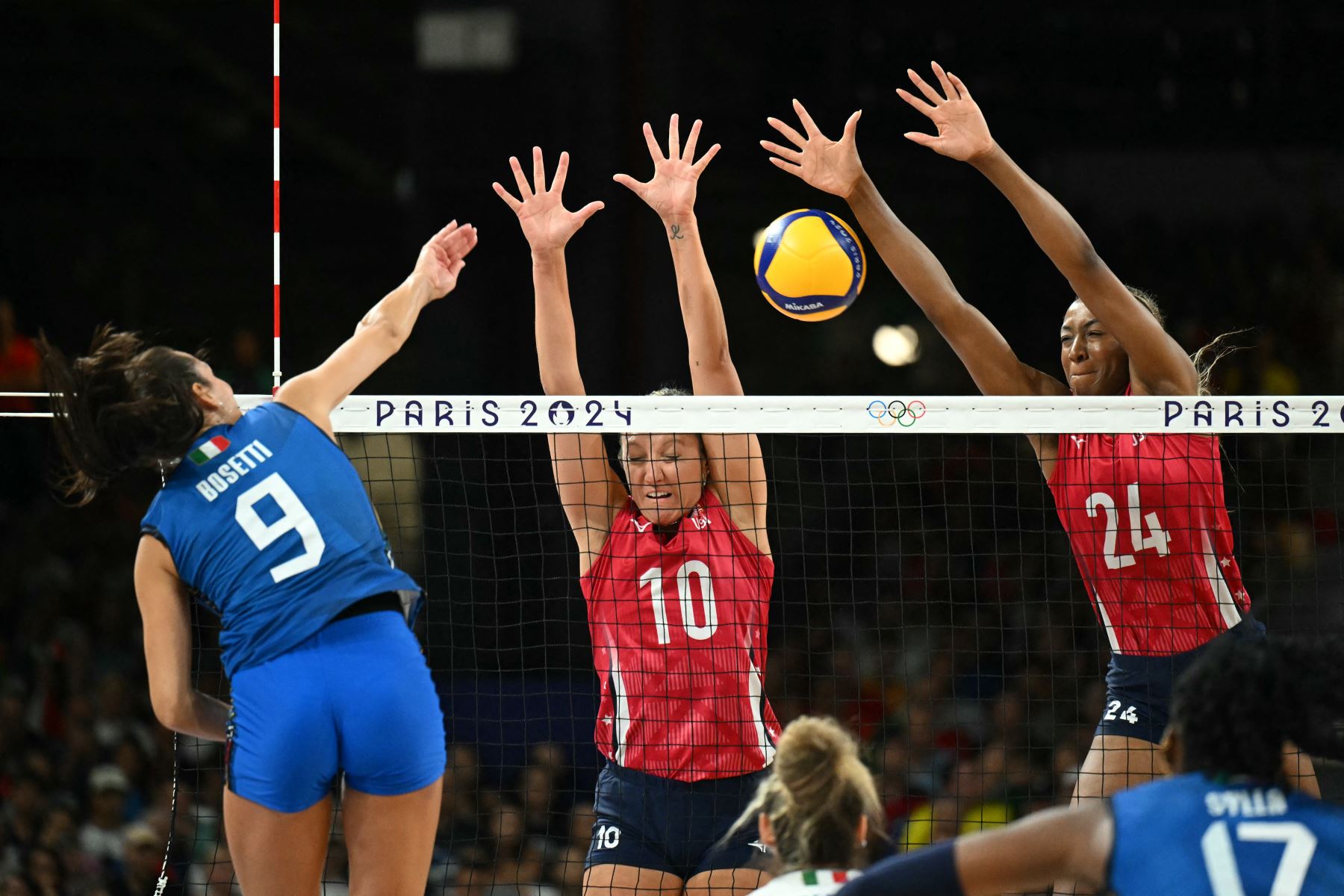 EE. UU., Jordan Larson,  Chiaka Ogbogu, saltan para bloquear un balón de la italiana Caterina Chiara Bosetti,  en el partido por la medalla de oro de voleibol femenino entre EE. UU. e Italia en el South Paris Arena 1 en París durante los Juegos Olímpicos de París 2024. AFP