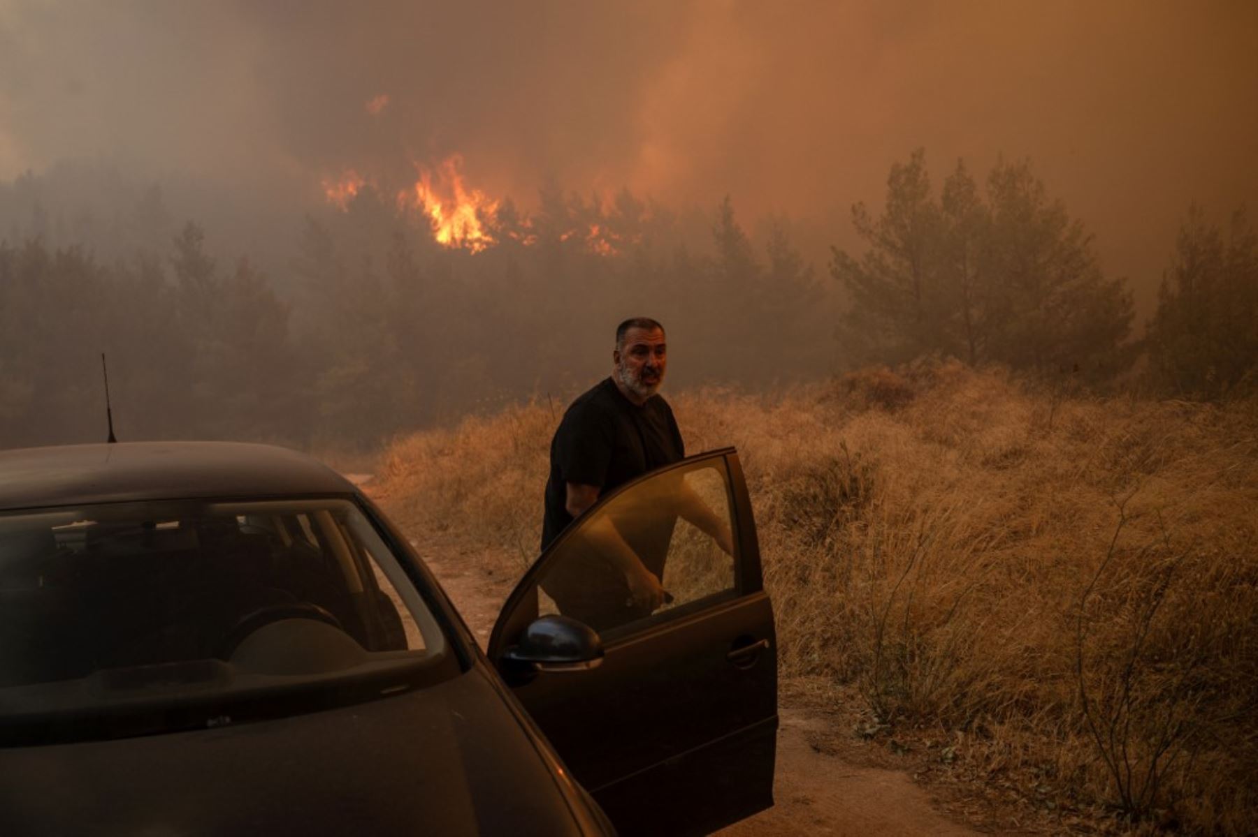 Una persona se sube a su coche frente a las llamas para evacuar durante un incendio forestal en Dione. Foto: AFP