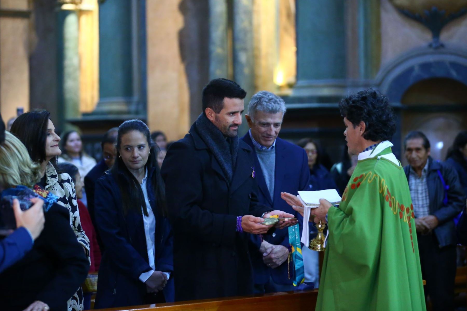 Sacerdote de iglesia Nazarenas bendice medalla olímpica obtenida por velerista, quien acudió con su familia a la iglesia. Foto: ANDINA/Eddy Ramos