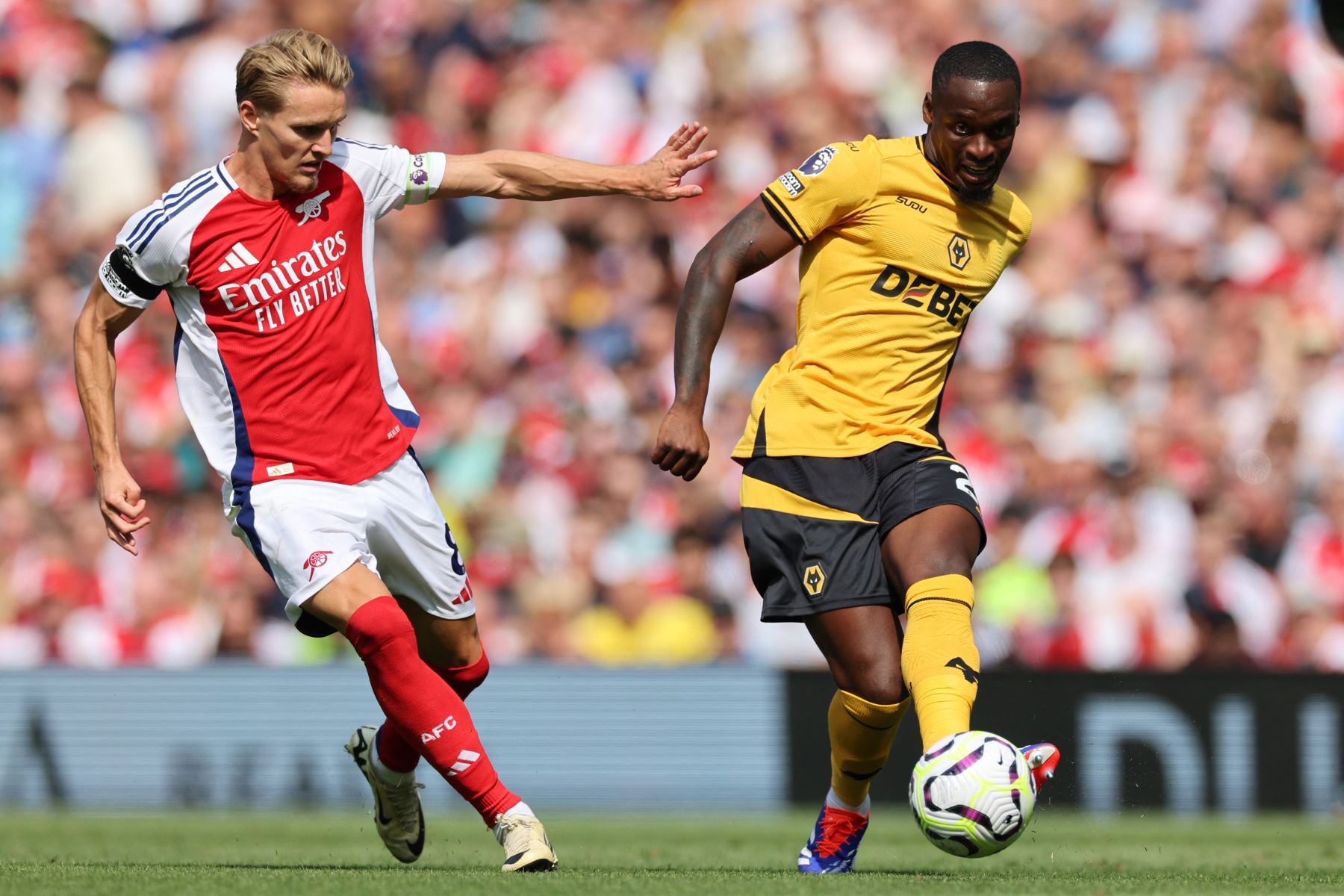 El defensor portugués de Wolverhampton Wanderers  Tote Gomes  pasa el balón bajo la presión del centrocampista noruego del Arsenal #08 Martin Odegaard durante el partido de fútbol de la Premier League inglesa entre Arsenal y Wolverhampton. AFP