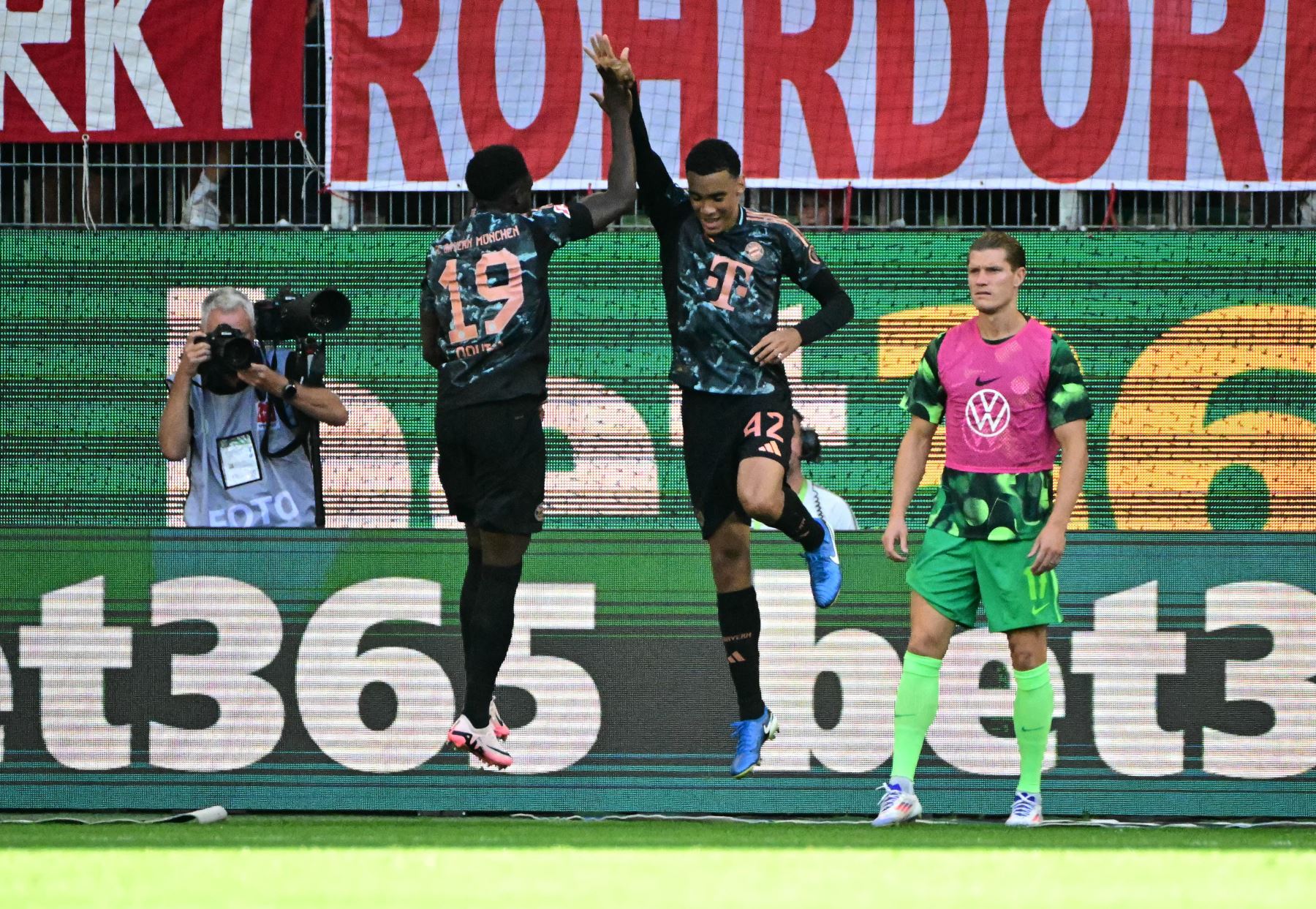 El centrocampista alemán del Bayern Munich Jamal Musiala celebra marcar el primer gol de su equipo con el defensor canadiense del Bayern Munich Alphonso Davies durante el partido de fútbol de la primera división alemana de la Bundesliga entre el VfL Wolfsburg y el FC Bayern Munich en Wolfsburg. AFP