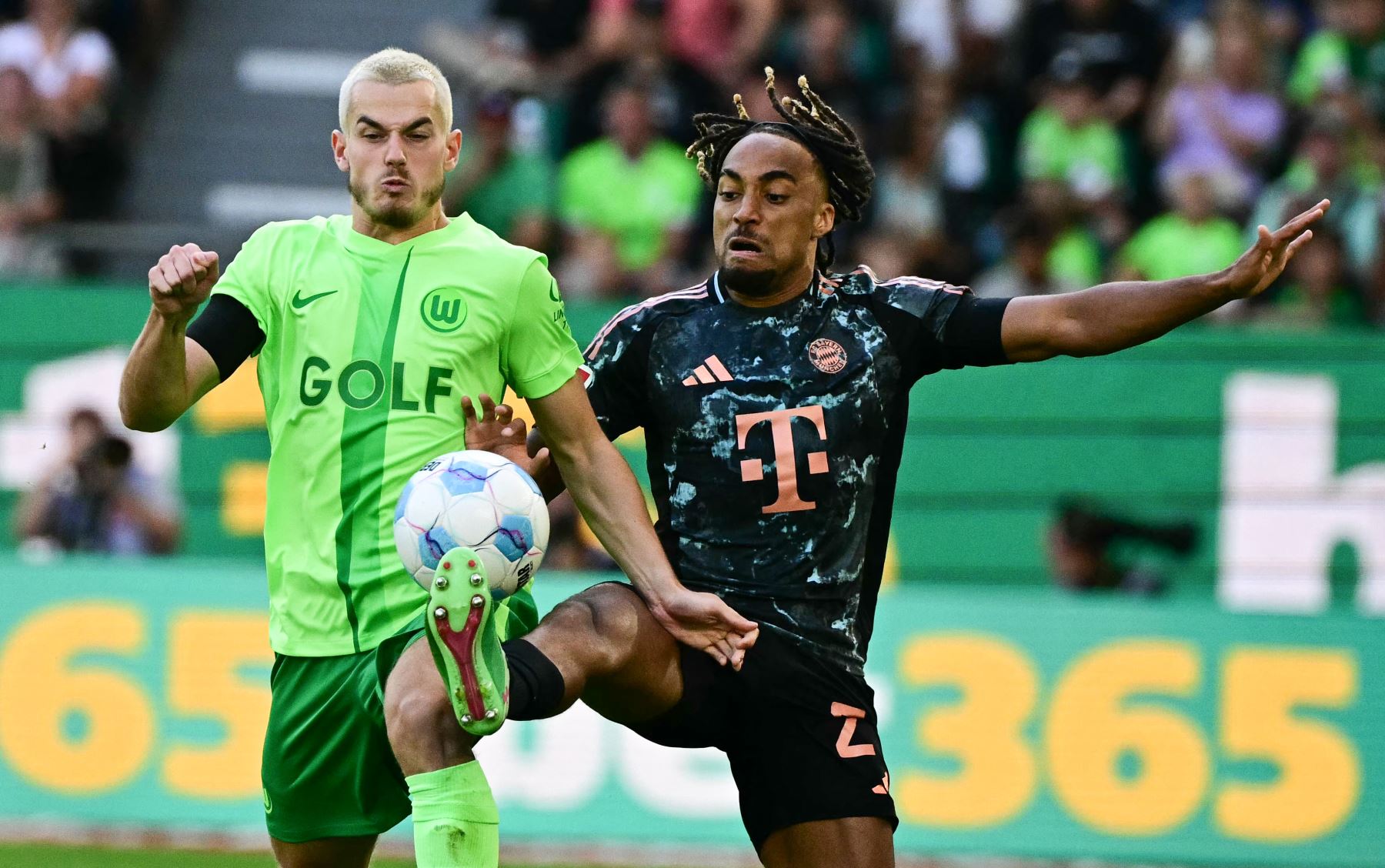 El defensor portugués del Bayern Munich Raphael Guerreiro  y el centrocampista polaco del Wolfsburg  Jakub Kaminski disputan el balón durante el partido de fútbol de la primera división alemana de la Bundesliga entre el VfL Wolfsburg y el FC Bayern Munich en Wolfsburg. AFP