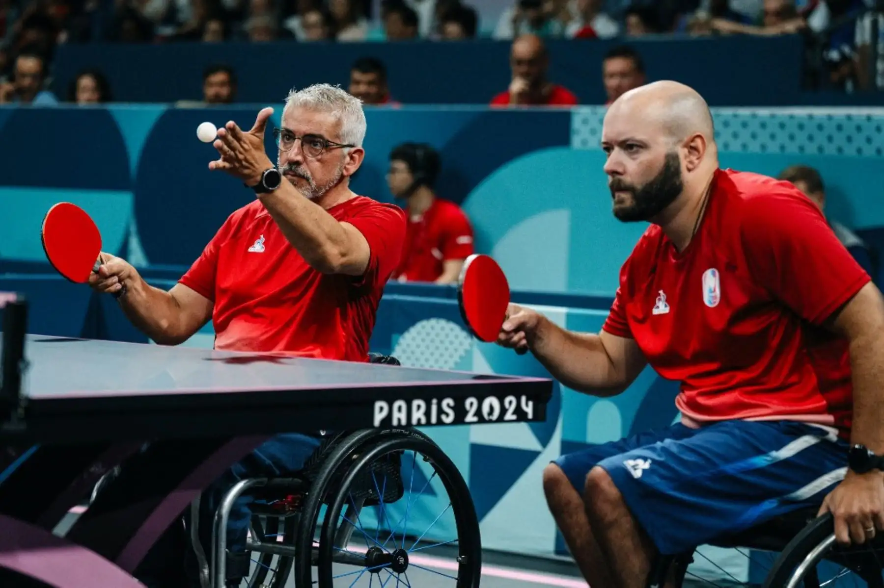 El francés Emeric Martin, sirve una pelota junto al francés Maxime Thamas durante su partido doble de tenis de mesa masculino de octavos de final (clase 4-3) entre Australia y Francia en los Juegos Paralímpicos París 2024 . Foto: AFP