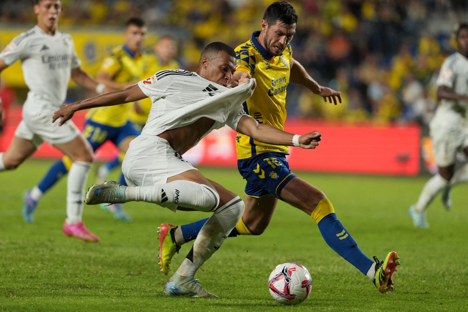 El delantero francés del Real Madrid  Kylian Mbappé lucha por el balón con el defensor escocés de Las Palmas  Scott McKenna durante el partido de fútbol de la liga española entre la UD Las Palmas y el Real Madrid CF. AFP