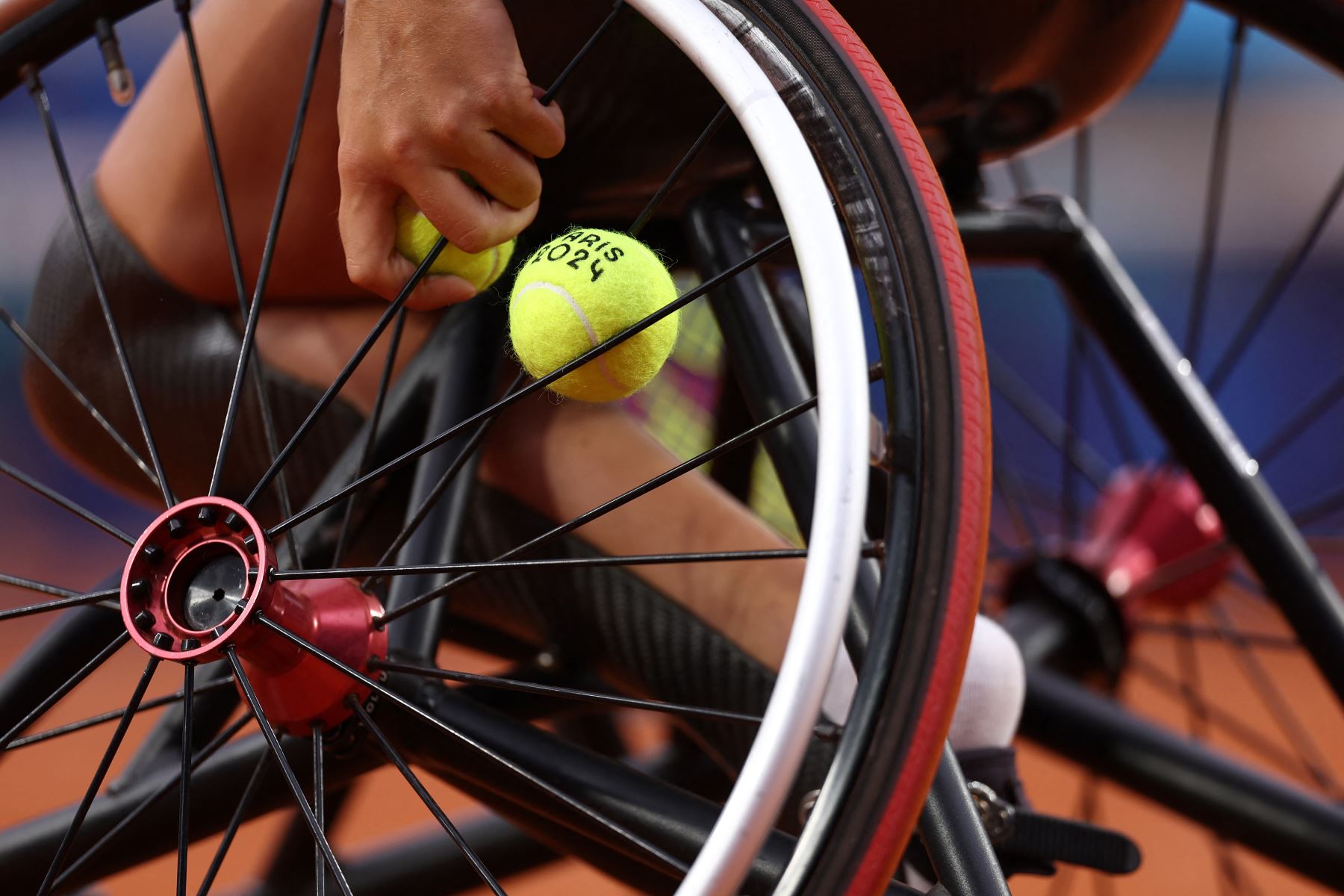 Una tenista agarra una pelota de tenis atrapada en los radios de su silla de ruedas durante la primera ronda del partido de tenis de dobles femenino en silla de ruedas entre Gran Bretaña y Holanda en la cancha Suzanne Lenglen en el estadio Roland-Garros durante los Juegos Paralímpicos París 2024

Foto: AFP