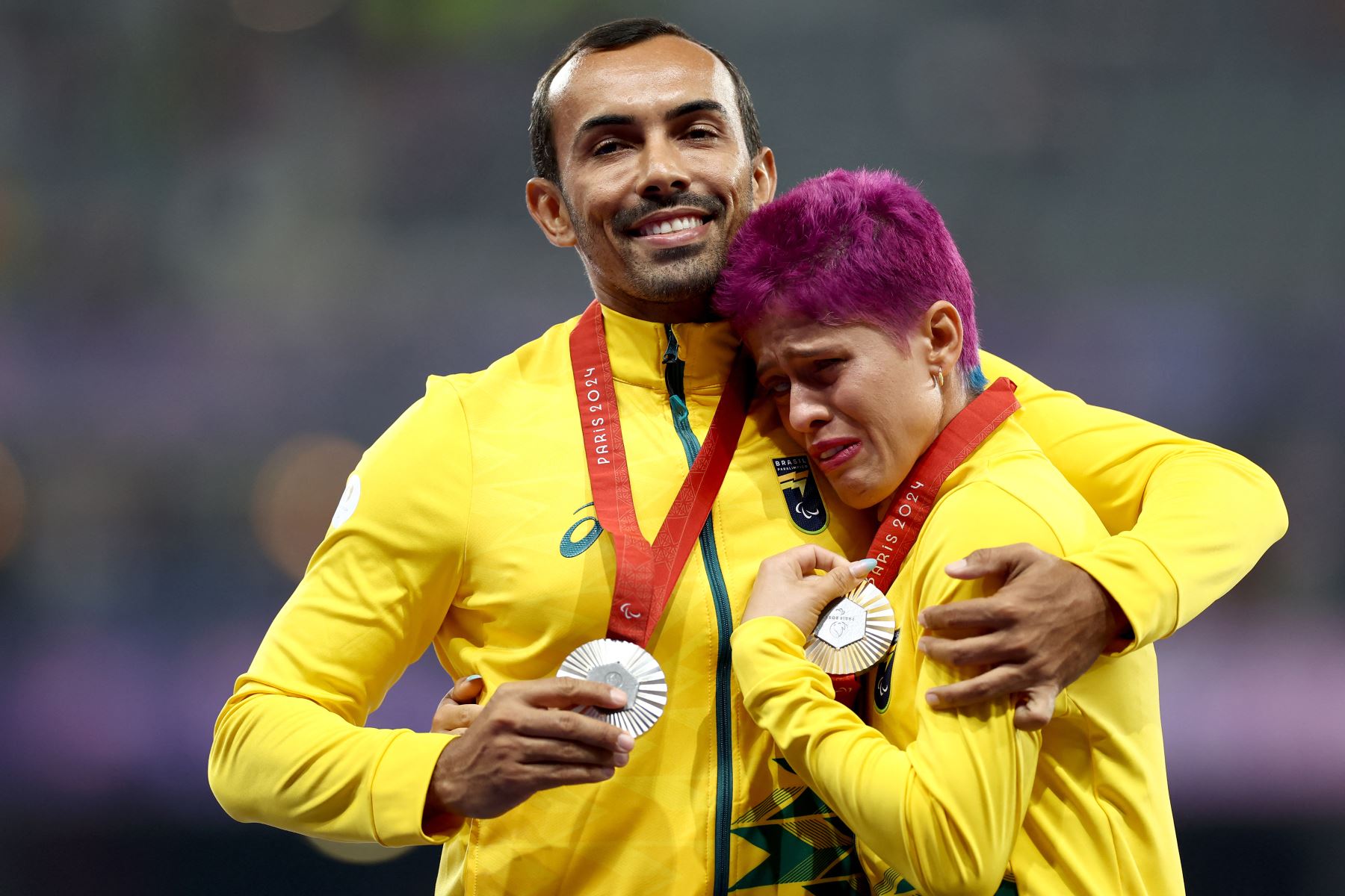 La atleta brasileña, medallista de plata, Simplicio da Silva Thalita Vitoria  y su guía Veloso da Silva Felipe celebran en el podio durante la ceremonia de victoria de la final de oro femenina de atletismo T11 400m de los Juegos Paralímpicos París 2024 en el Stade de France en Saint-Denis. , al norte de París.
Foto: AFP