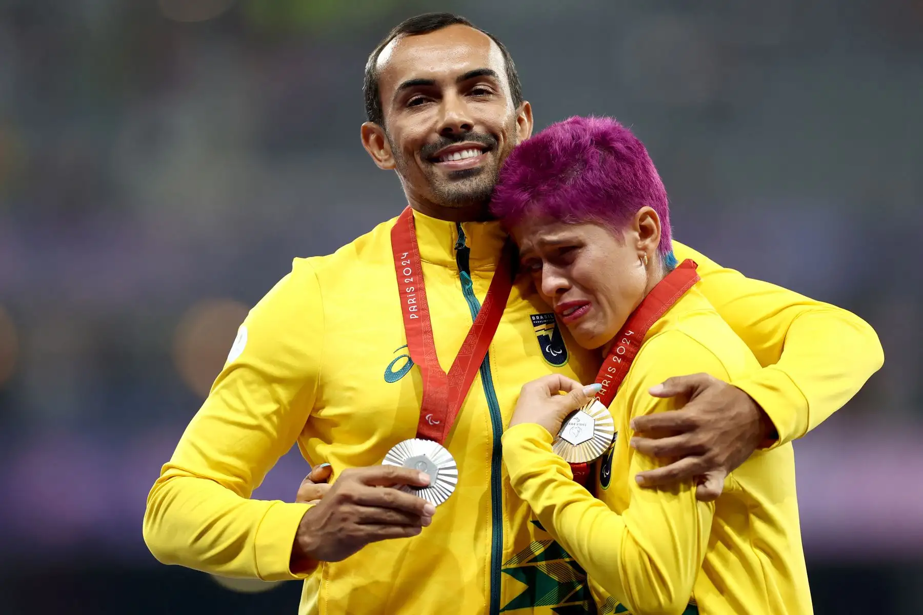 La atleta brasileña, medallista de plata, Simplicio da Silva Thalita Vitoria  y su guía Veloso da Silva Felipe celebran en el podio durante la ceremonia de victoria de la final de oro femenina de atletismo T11 400m de los Juegos Paralímpicos París 2024 en el Stade de France en Saint-Denis. , al norte de París.
Foto: AFP
