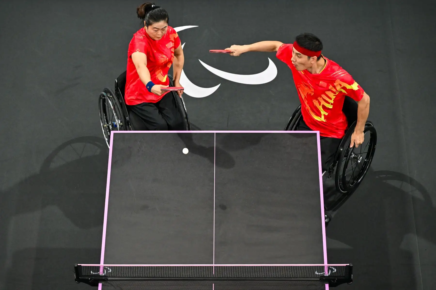 Esta imagen muestra a Ying Zhou (izq.) y Panfeng Feng de China compitiendo en el partido por la medalla de oro en dobles mixtos de tenis de mesa - XD7, durante los Juegos Paralímpicos de París 2024. 
Foto. ANDINA/AFP